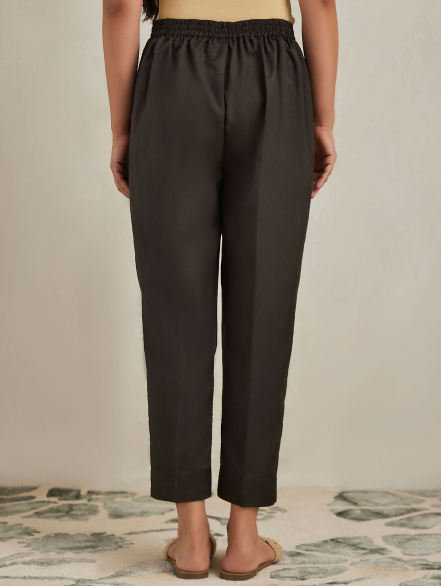 Person wearing brown pants on a neutral background