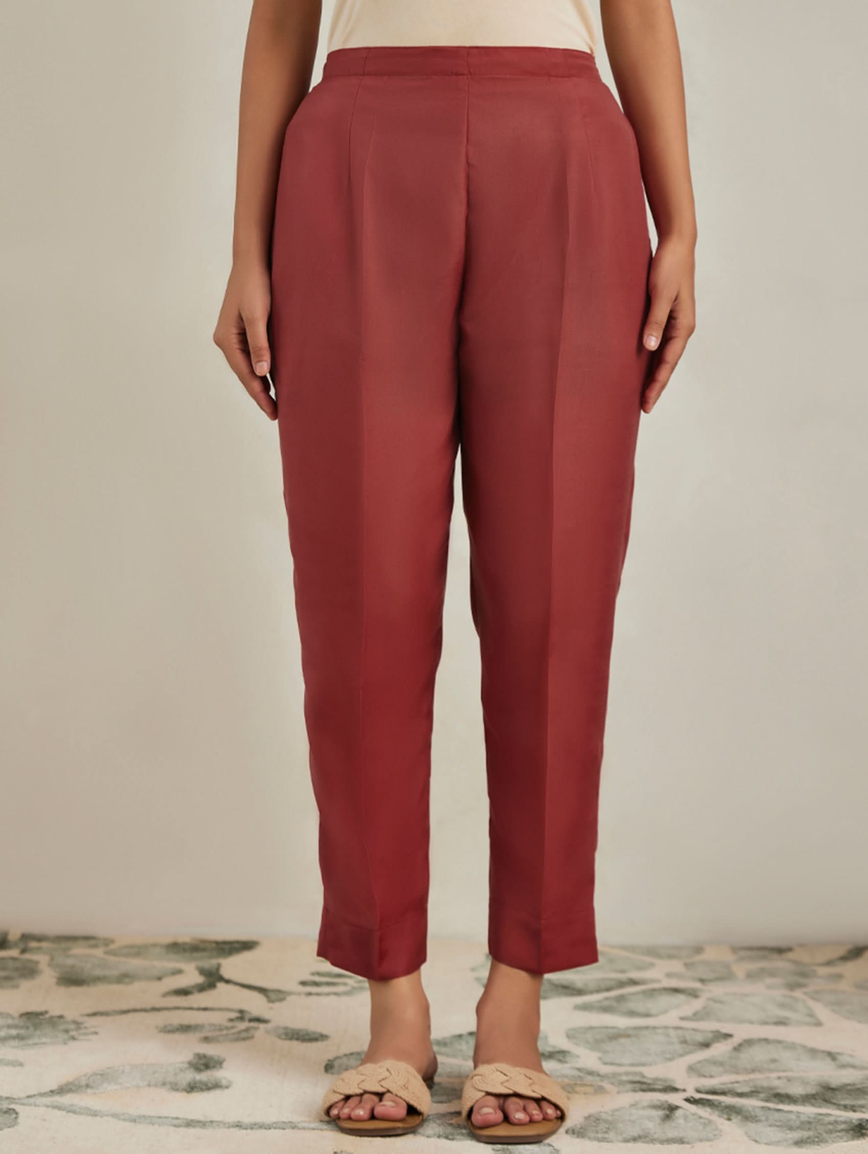 Person wearing red pants standing on a patterned rug with a neutral background