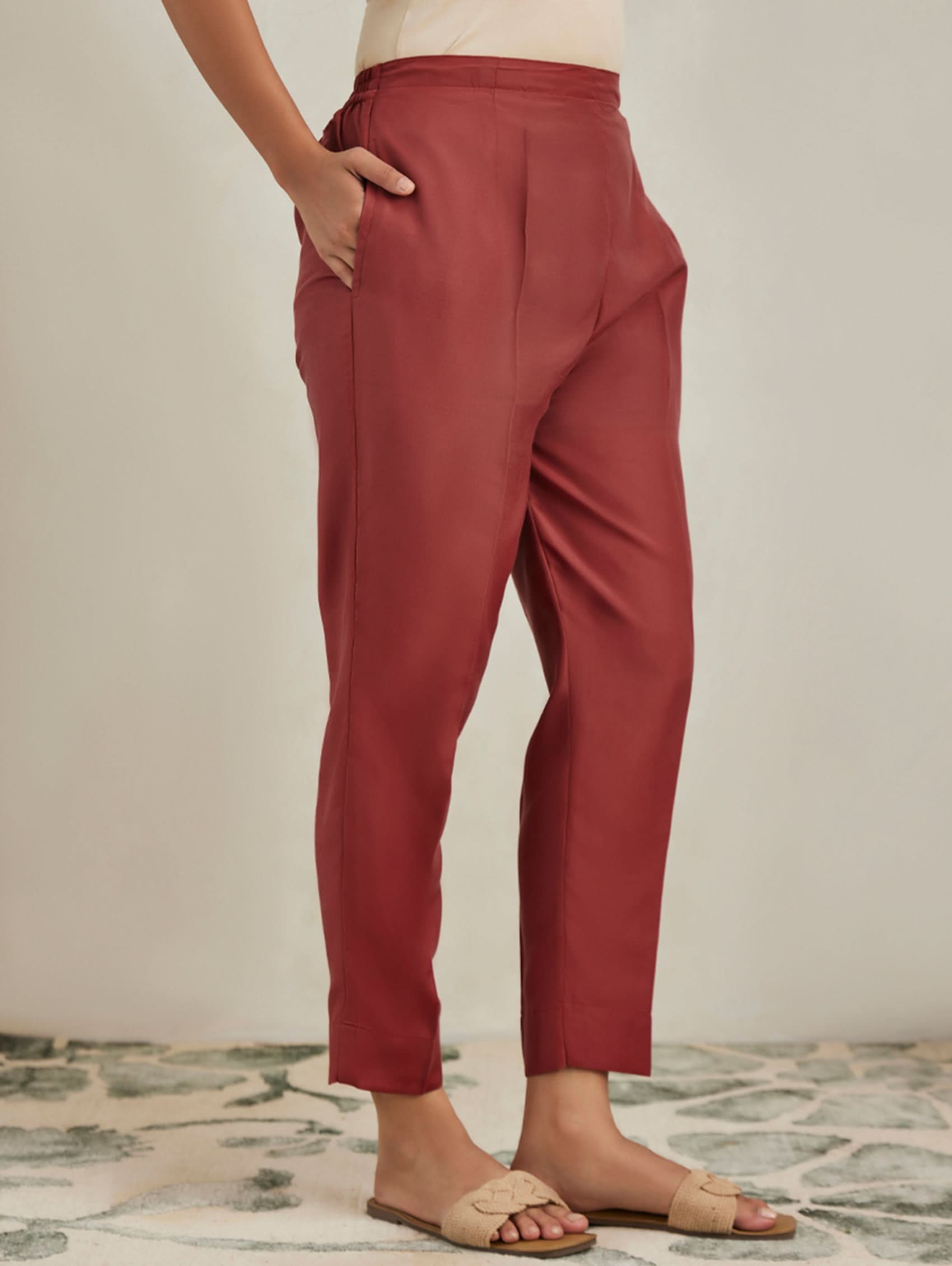 Person wearing red pants standing on a patterned rug with a neutral background