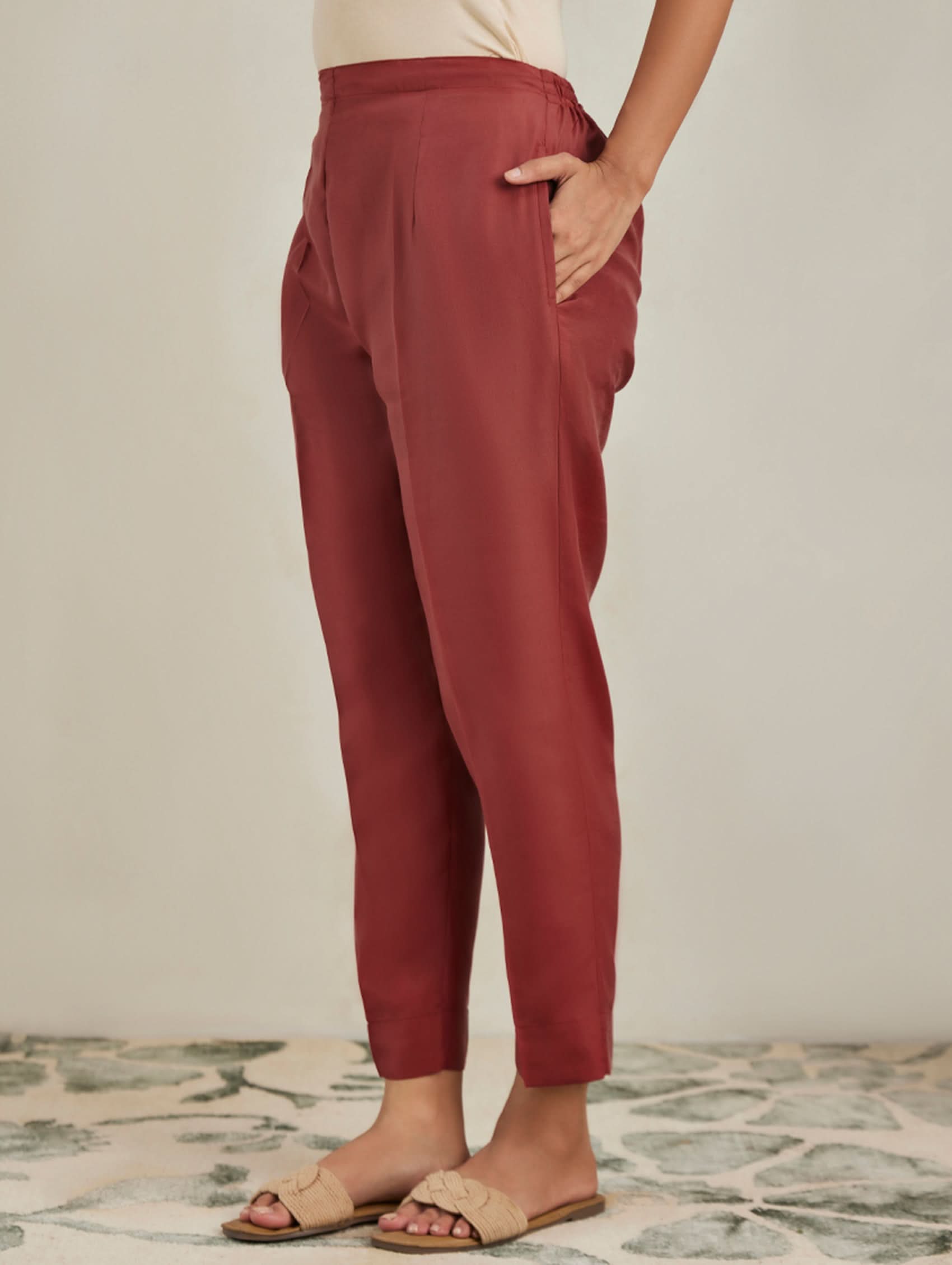 Person wearing red pants standing on a patterned floor with a neutral background