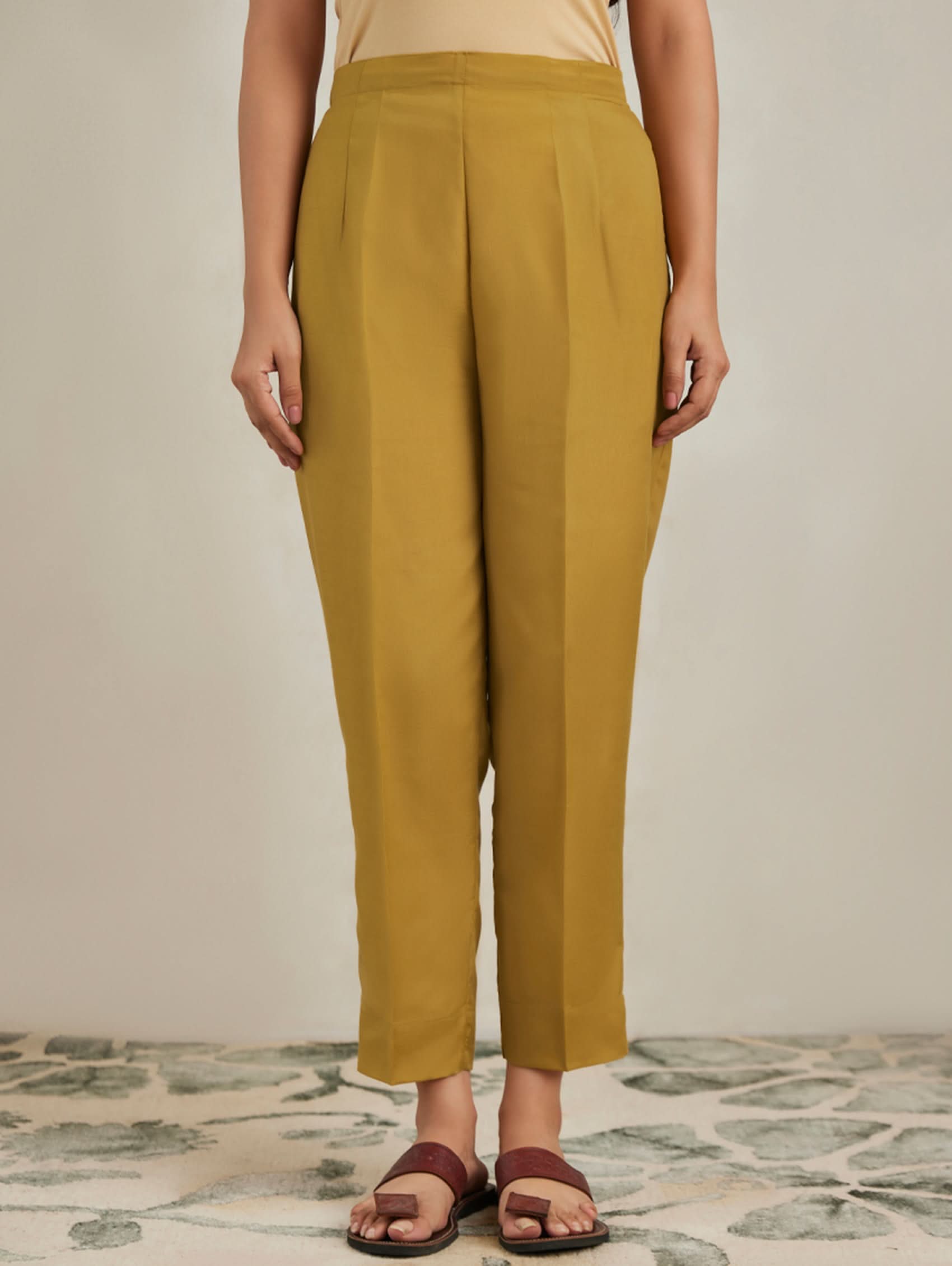 Person wearing mustard yellow pants on a neutral background