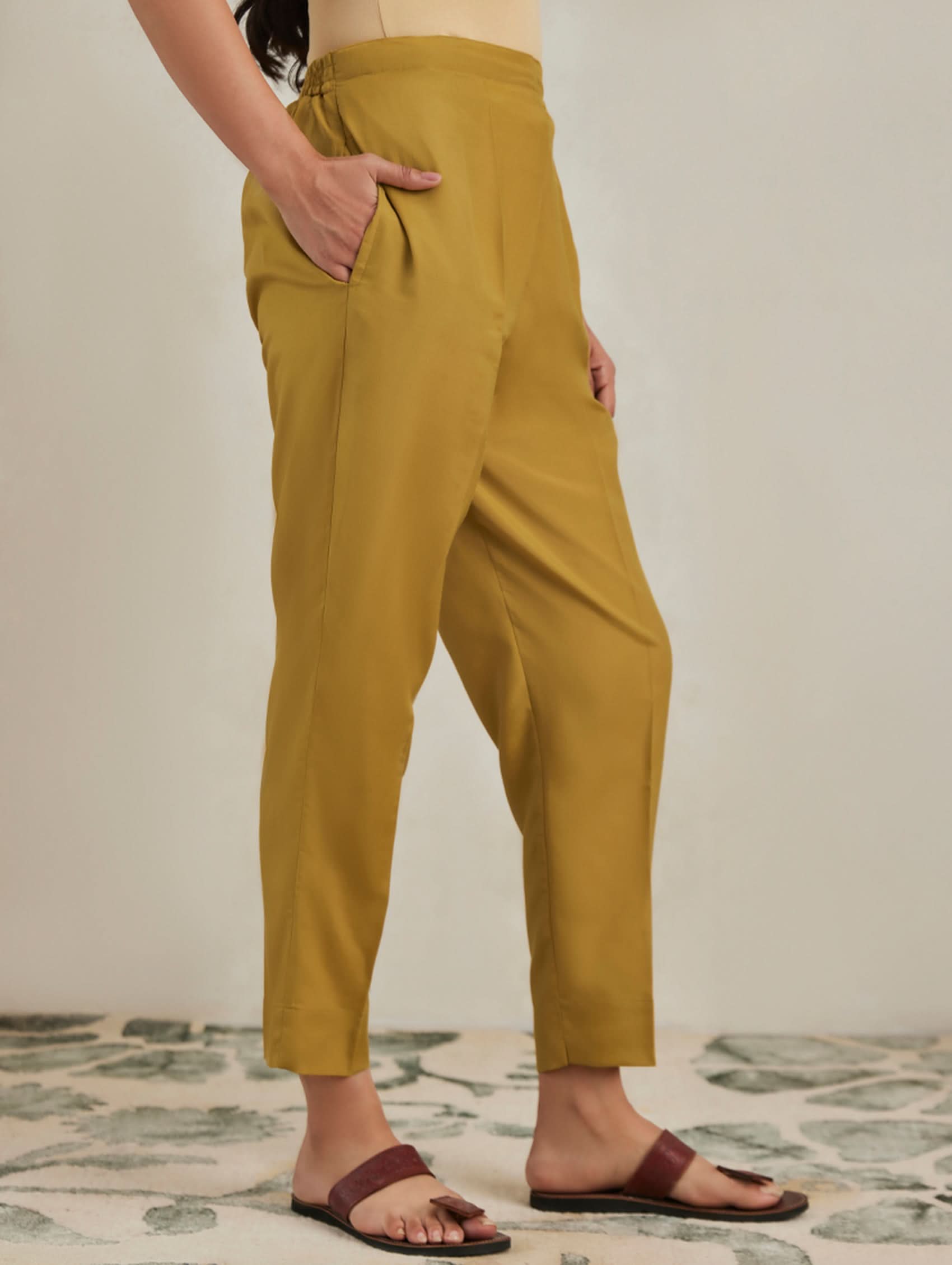 Person wearing mustard yellow pants standing on a patterned rug.