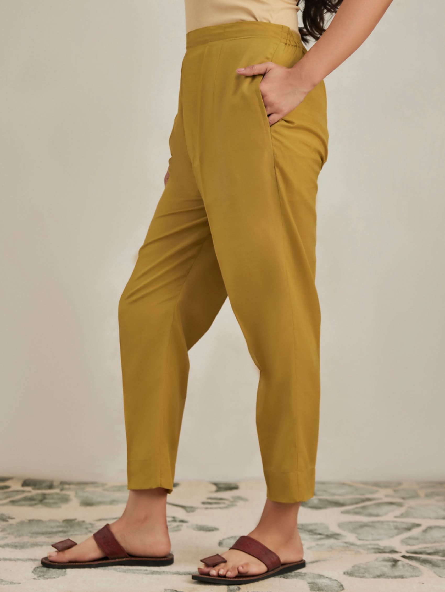 Person wearing mustard yellow pants with a neutral background