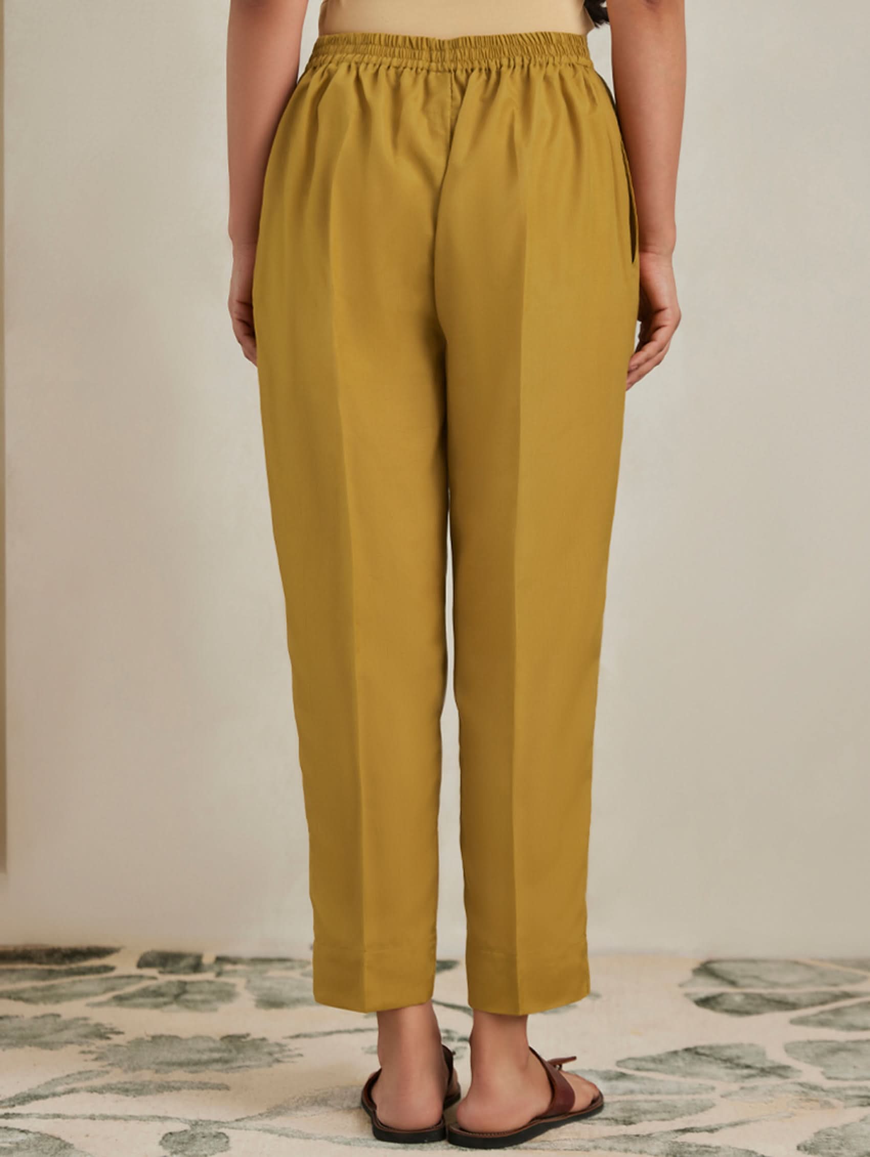 Mustard yellow pants worn by a person on a neutral background