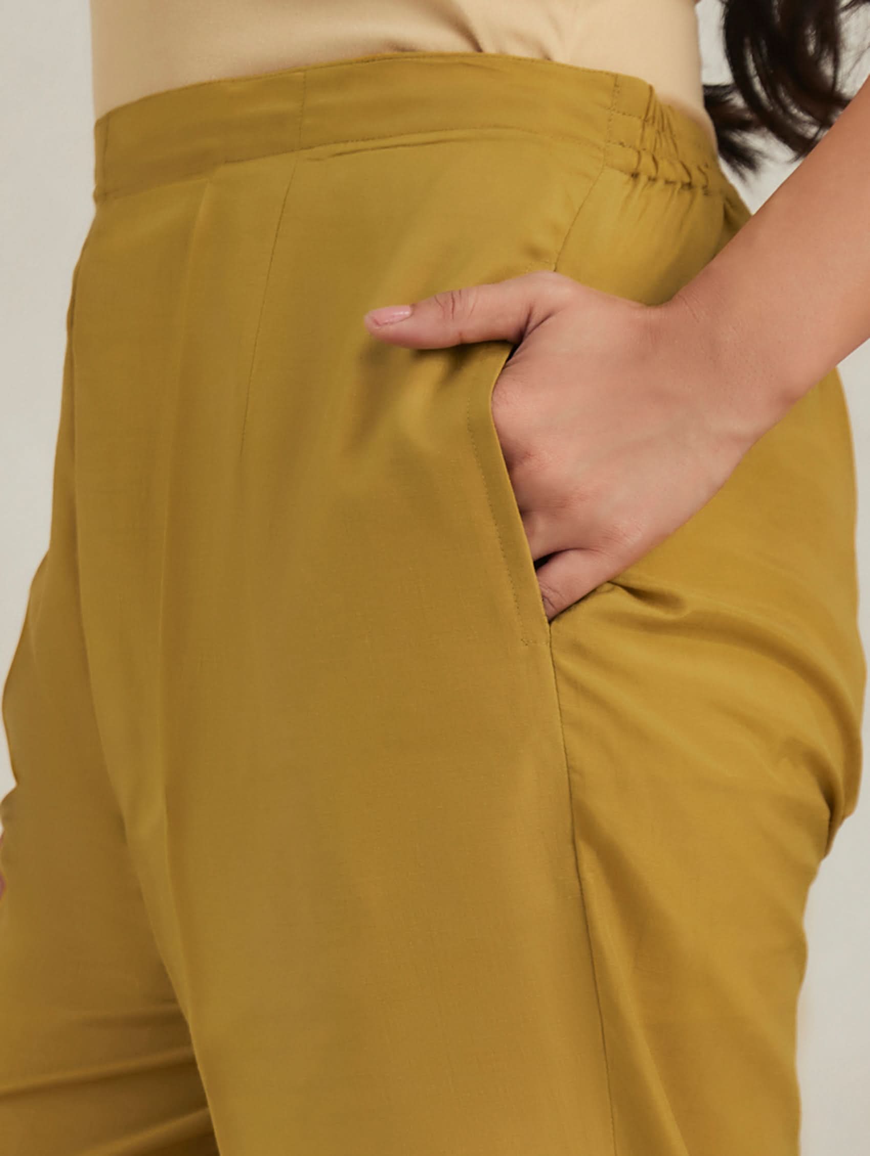 Mustard yellow pants worn by a person with a neutral background