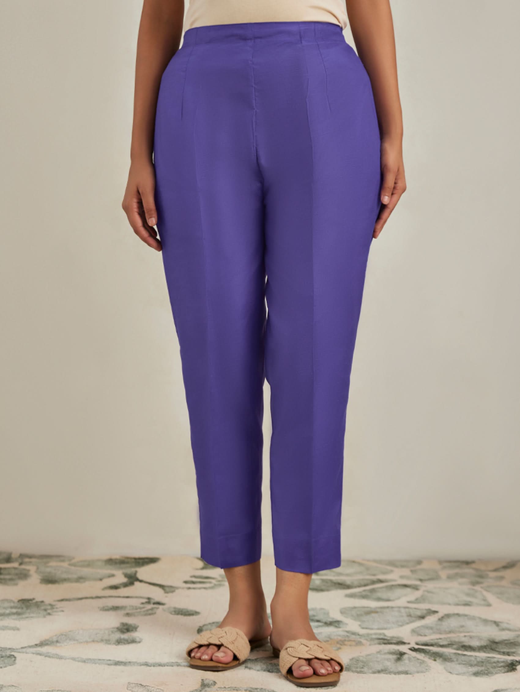 Purple pants worn by a person on a neutral background