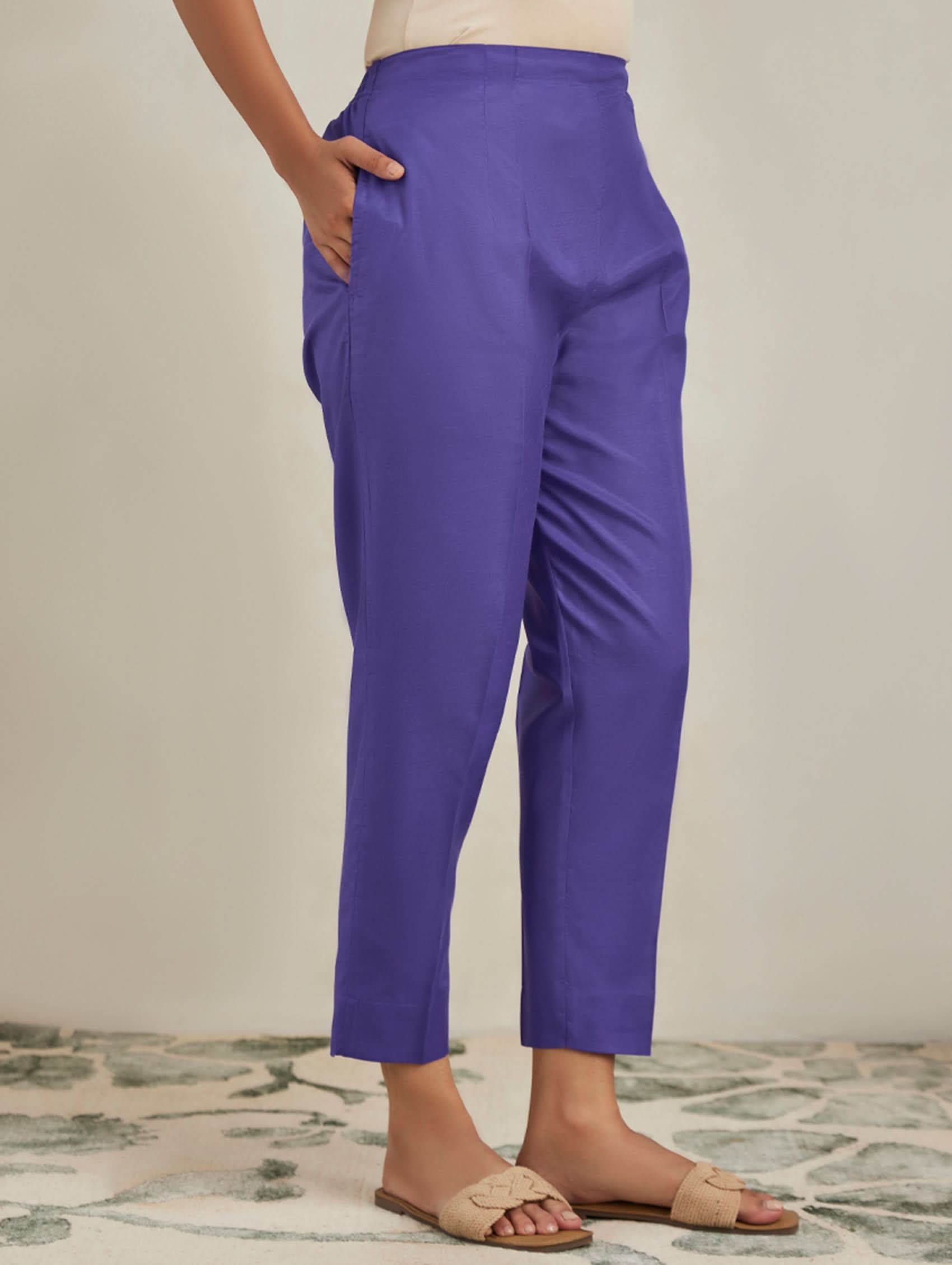Purple pants worn by a person on a neutral background