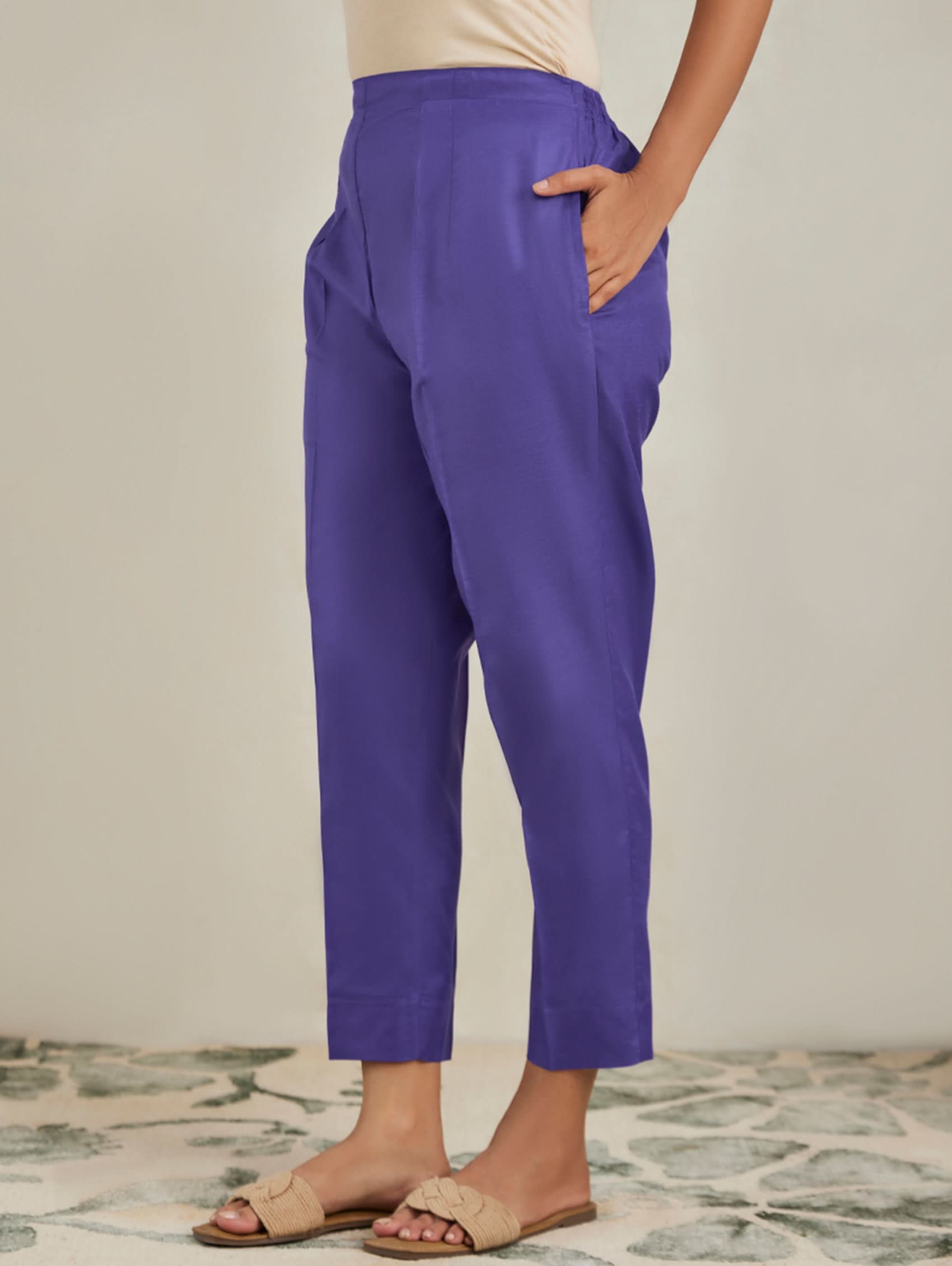 Purple pants worn by a person on a neutral background