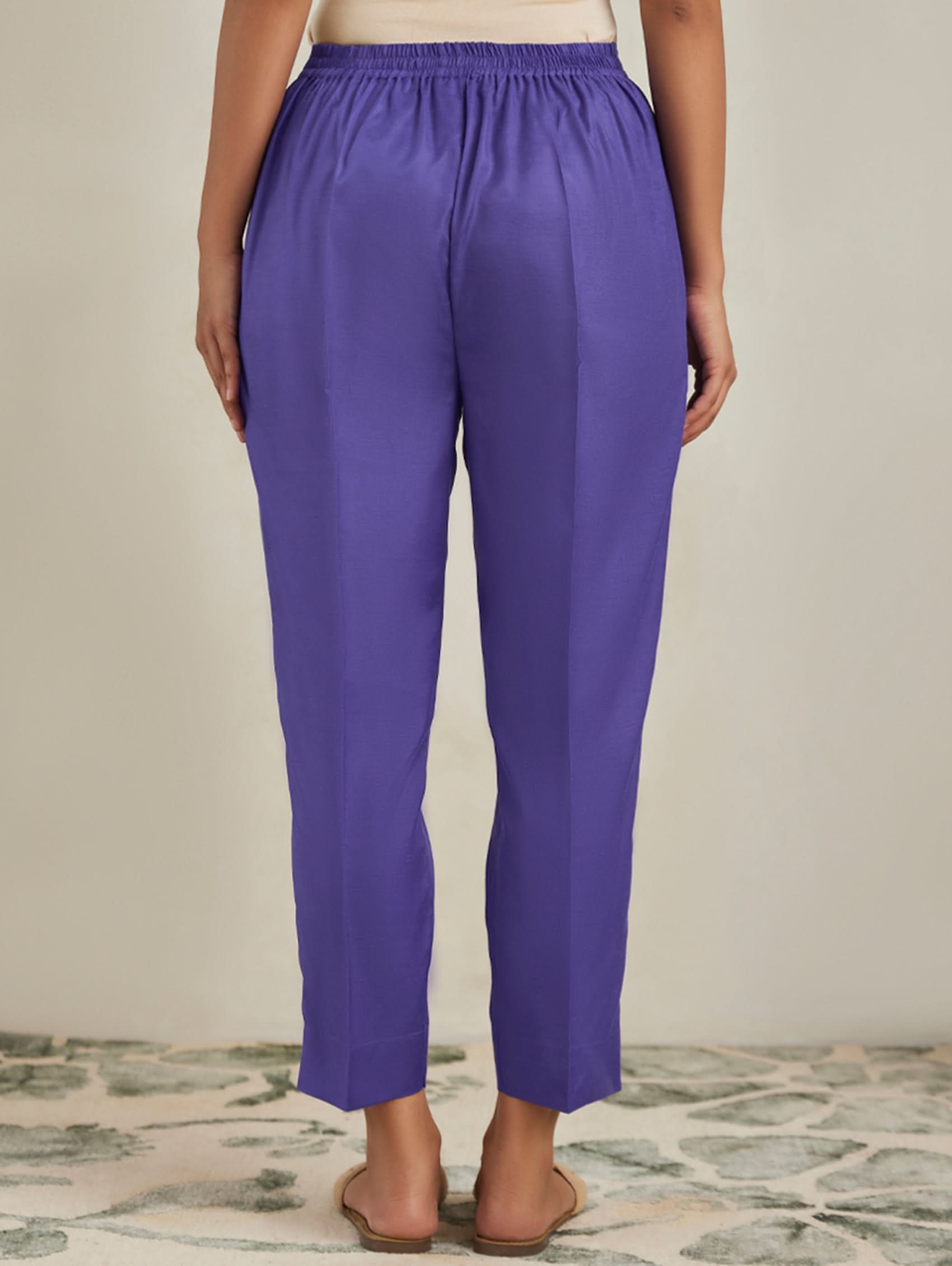 Purple pants worn by a person on a neutral background
