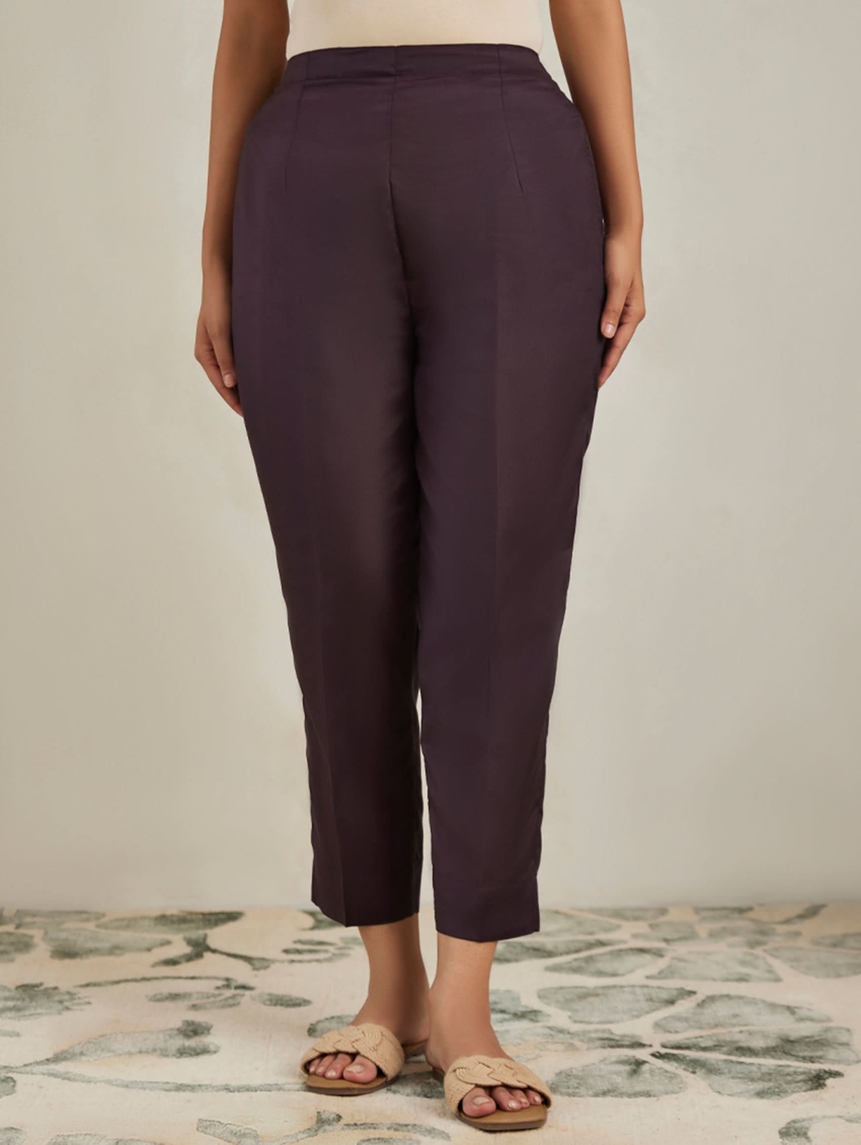 Person wearing dark purple pants on a neutral background