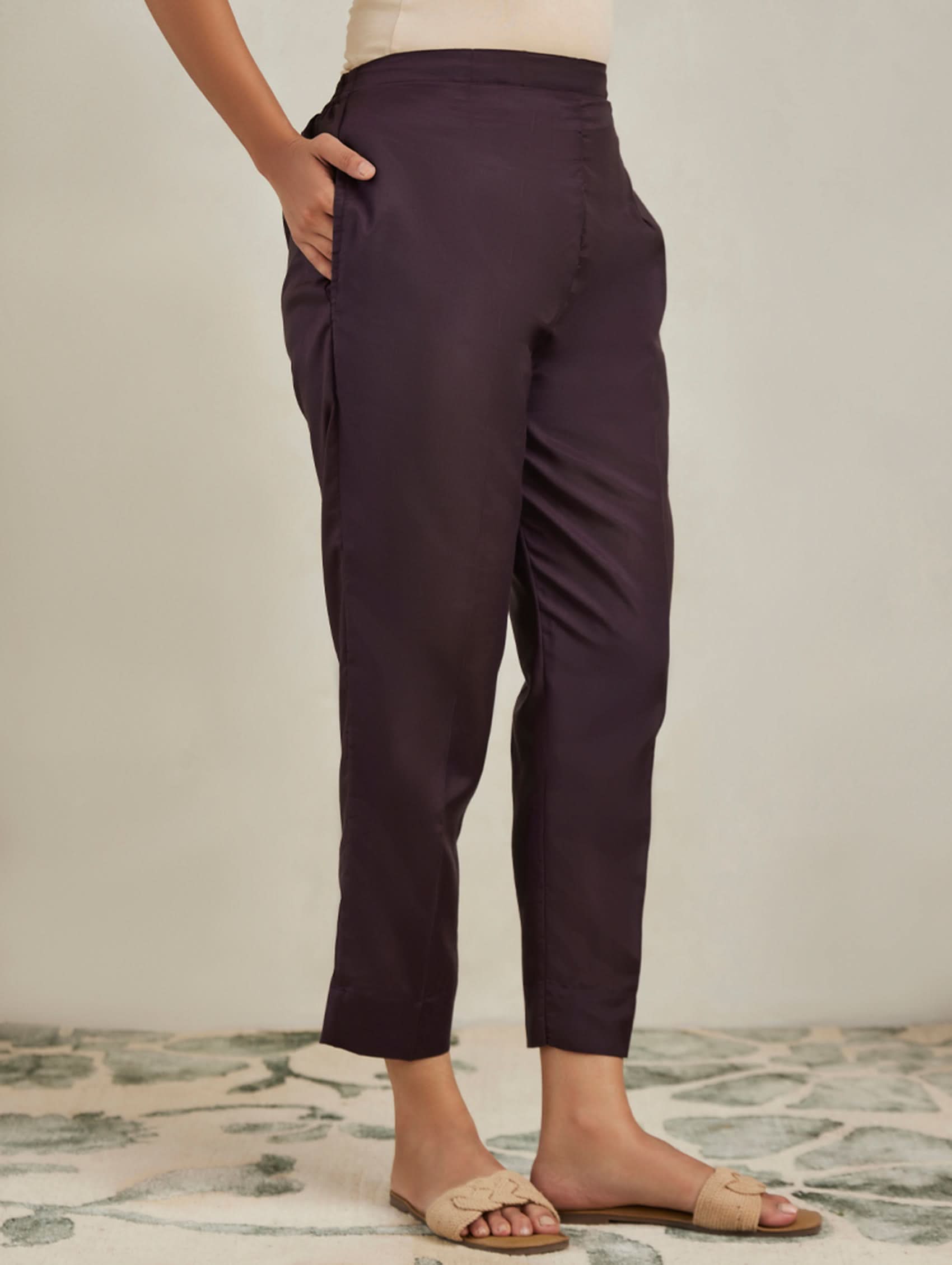 Dark purple pants worn by a person on a neutral background