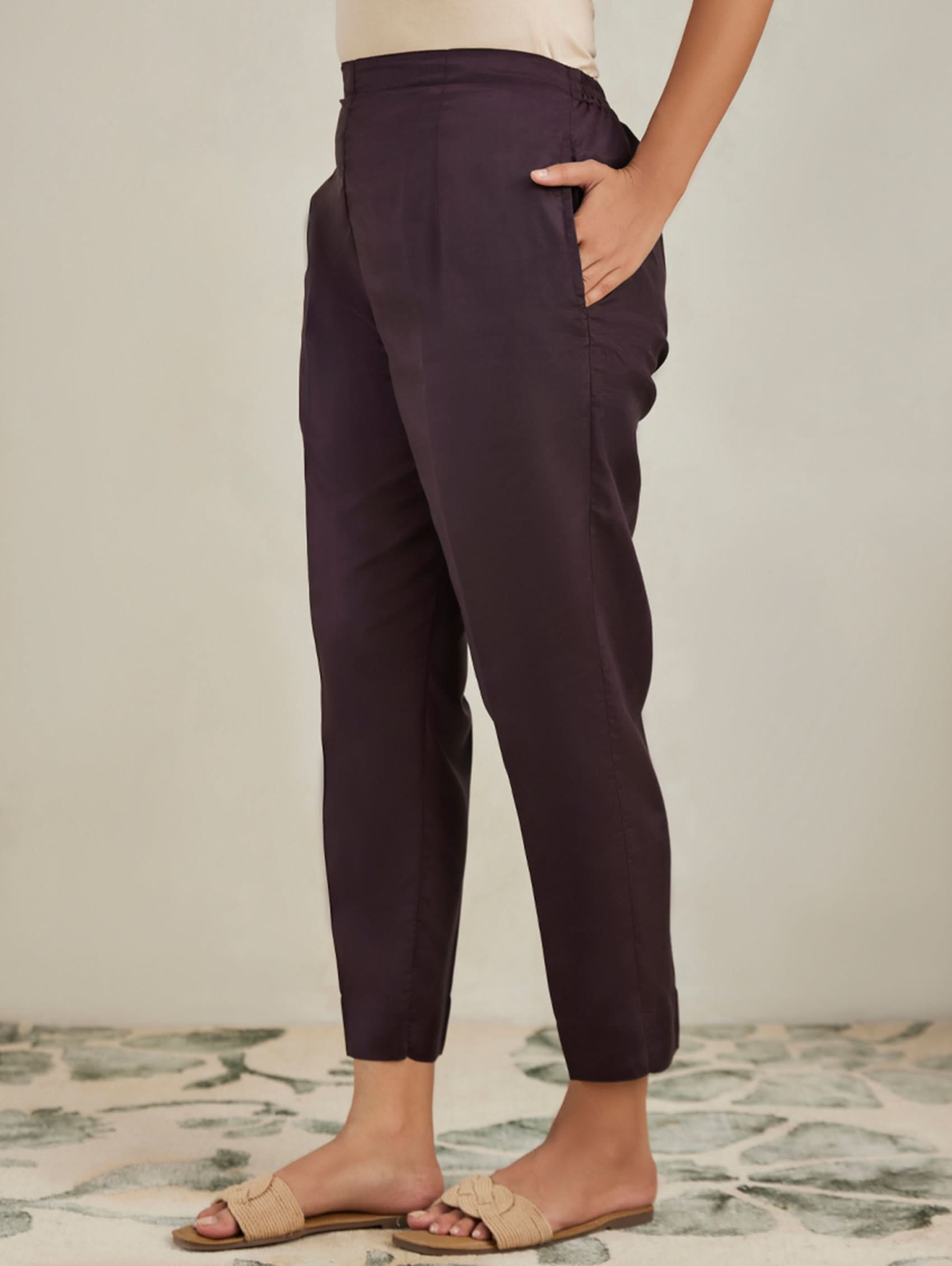 Person wearing dark purple pants with a neutral background