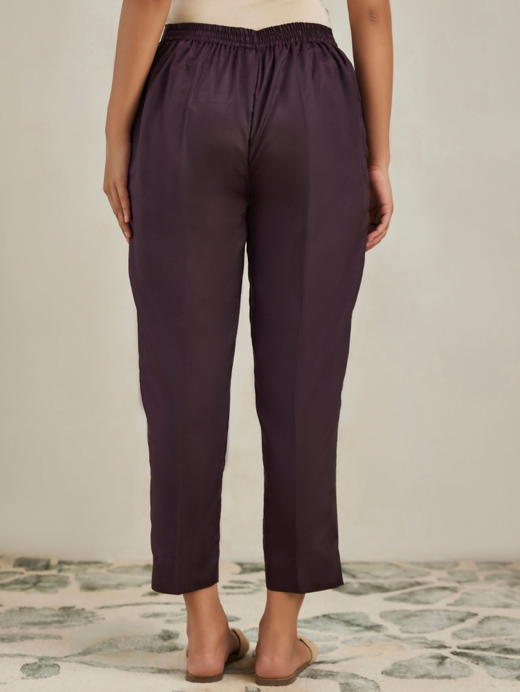 Person wearing dark purple pants on a neutral background