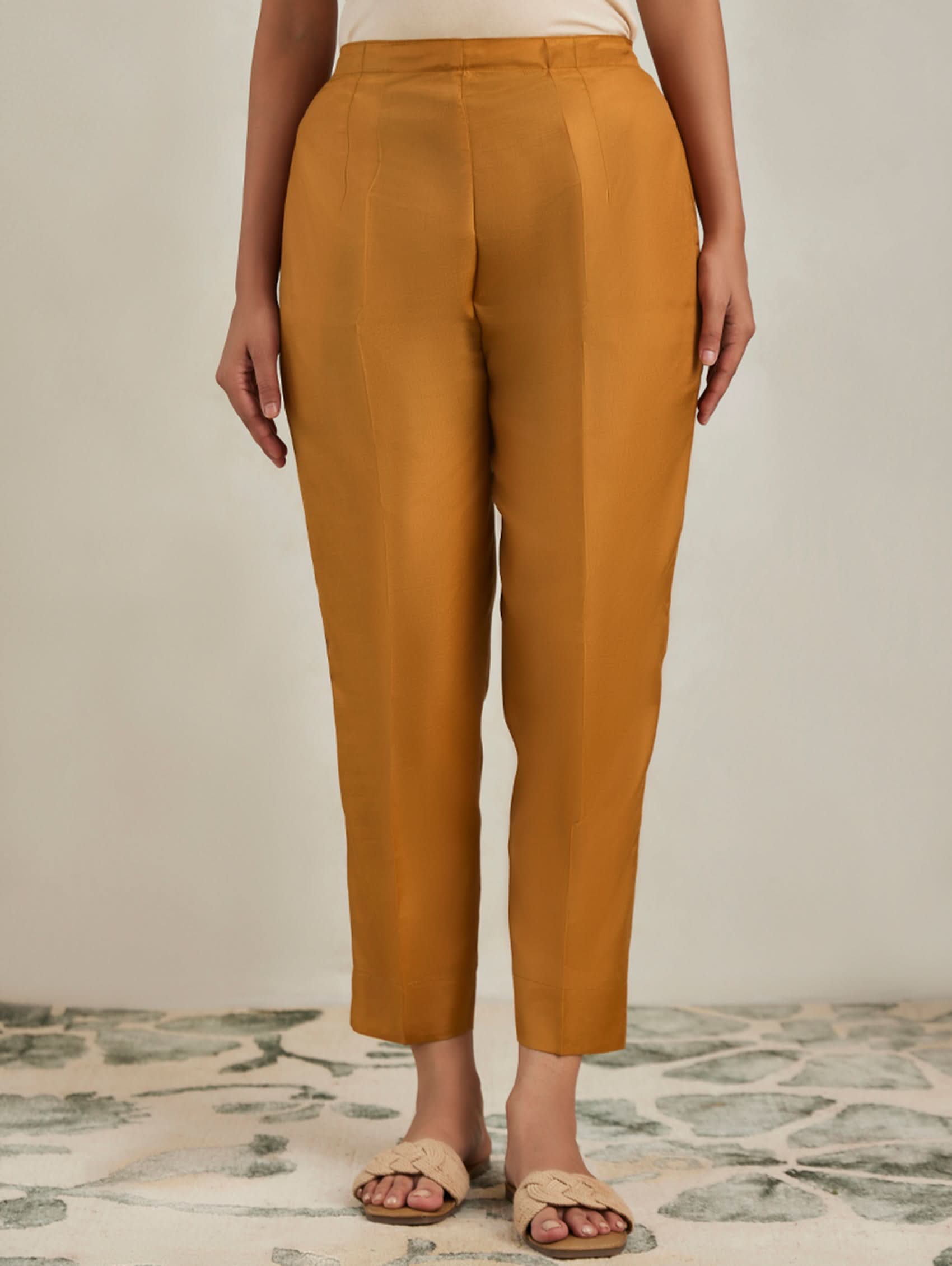 Mustard yellow pants worn by a person on a neutral background