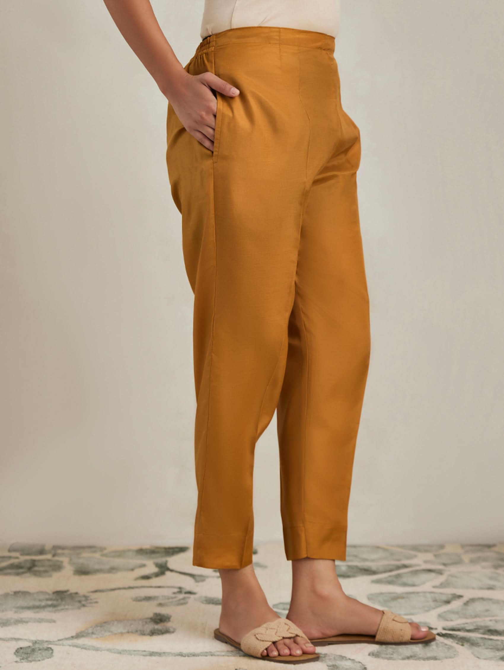 Mustard yellow pants worn by a person on a neutral background