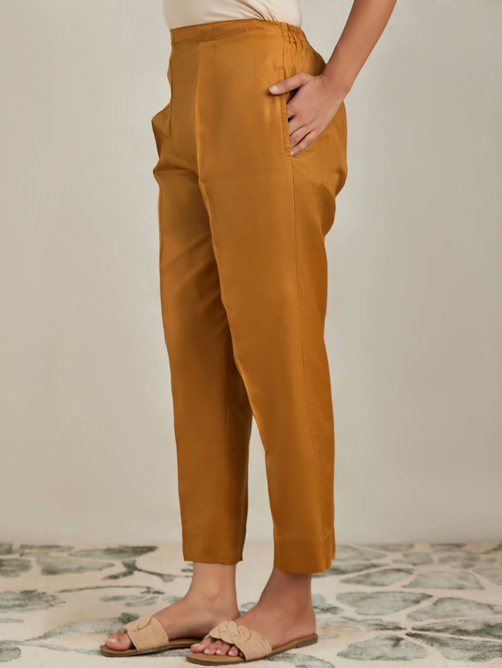 Person wearing mustard yellow pants standing on a patterned floor.