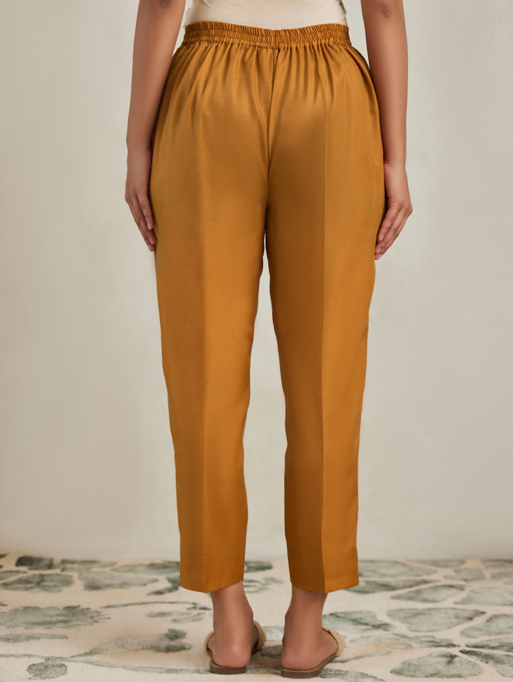 Mustard yellow pants worn by a person on a neutral background