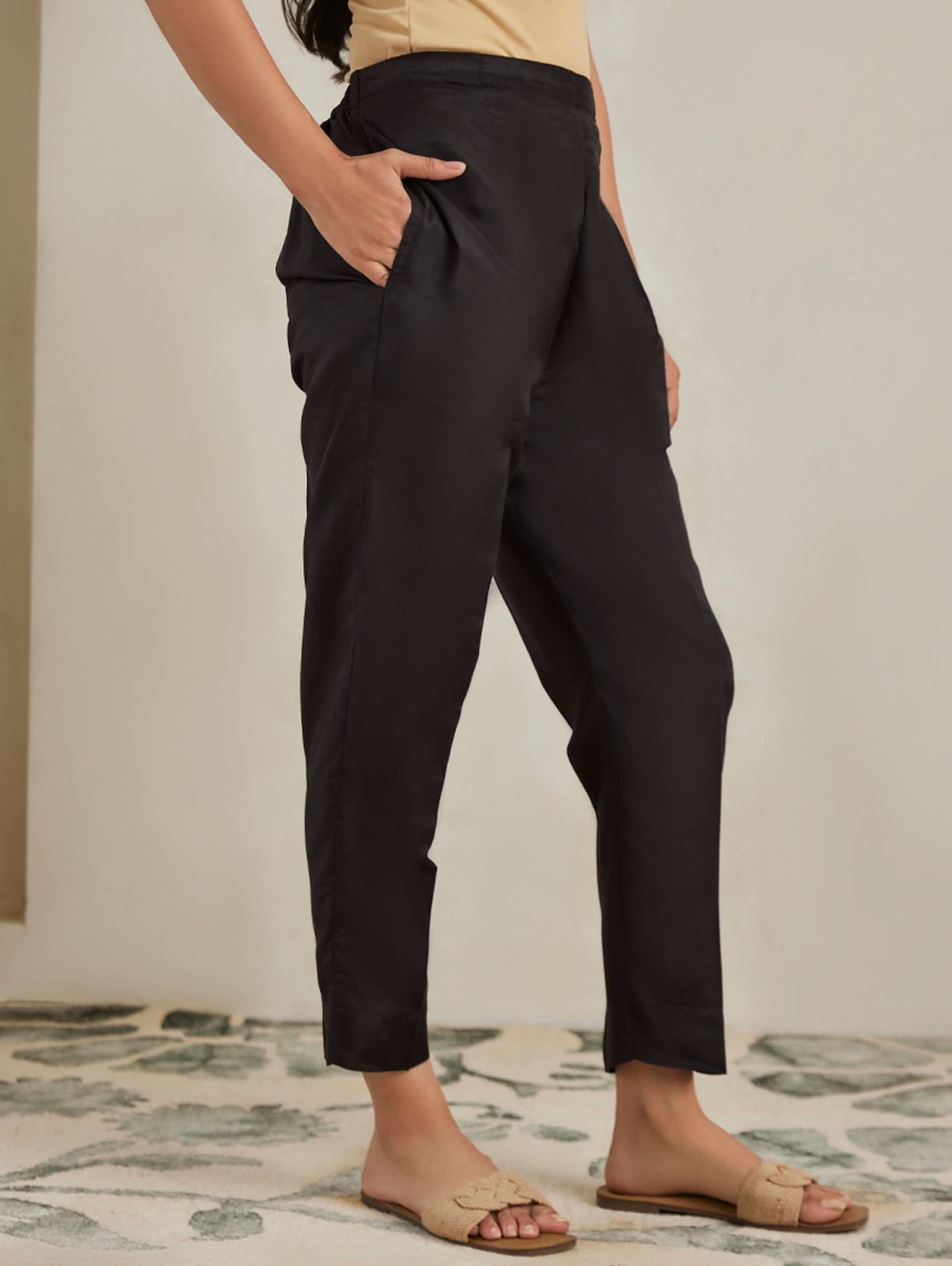 Person wearing black pants standing on a patterned rug.