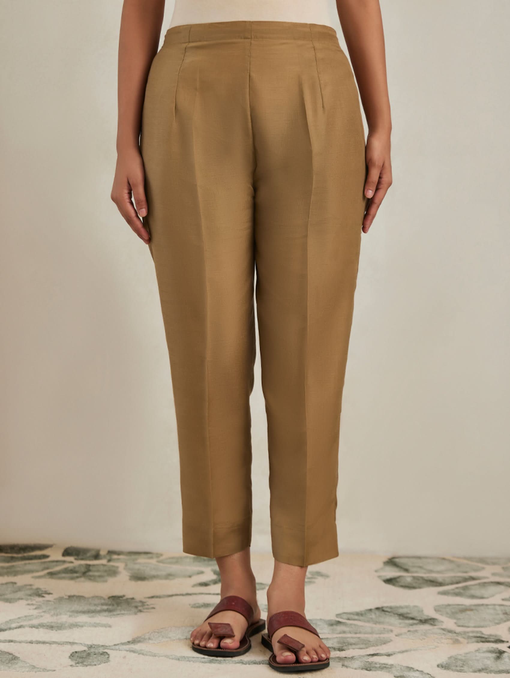 Person wearing tan pants on a neutral background