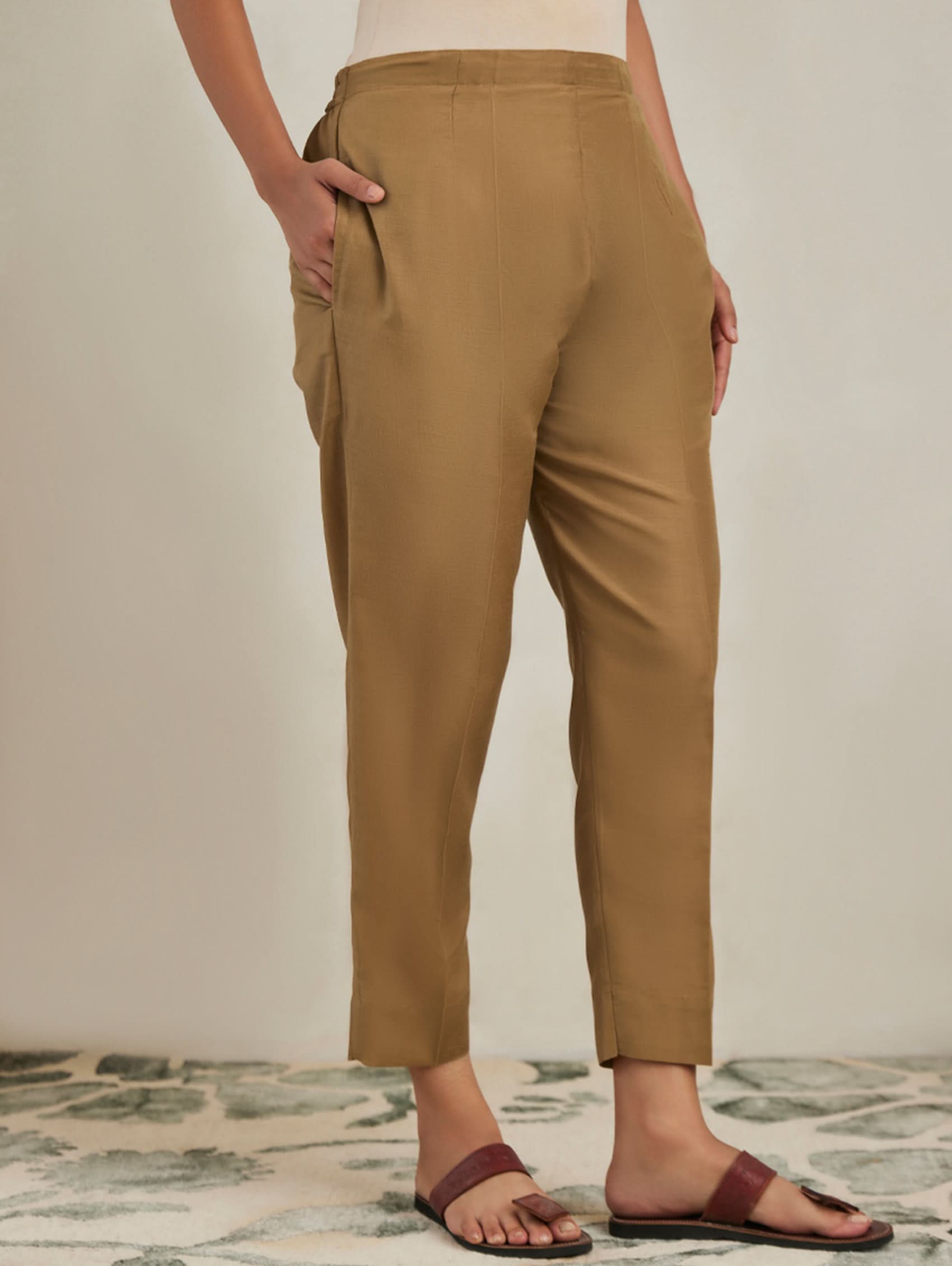 Person wearing tan pants on a neutral background