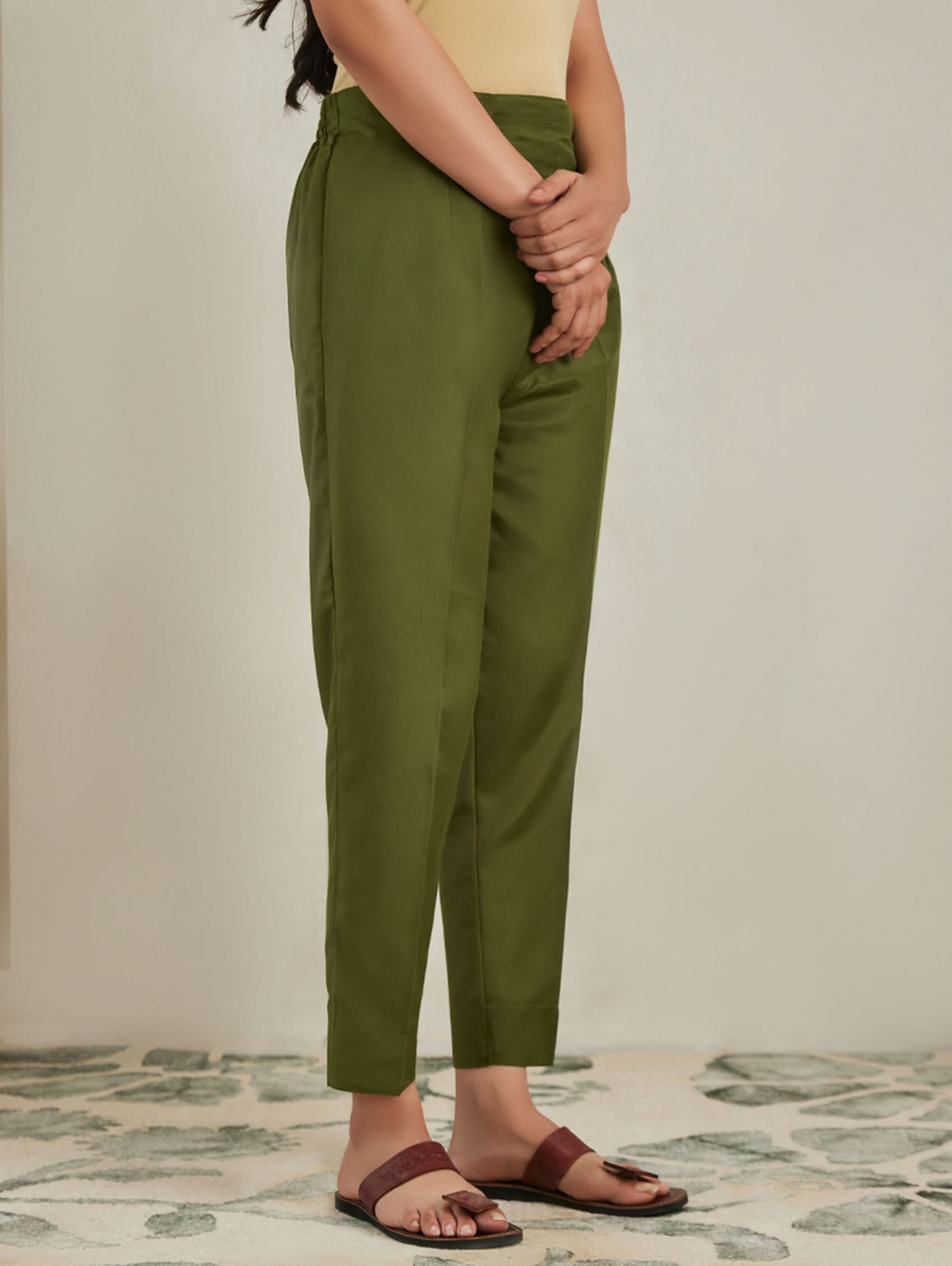 Person wearing green pants standing on a patterned floor.
