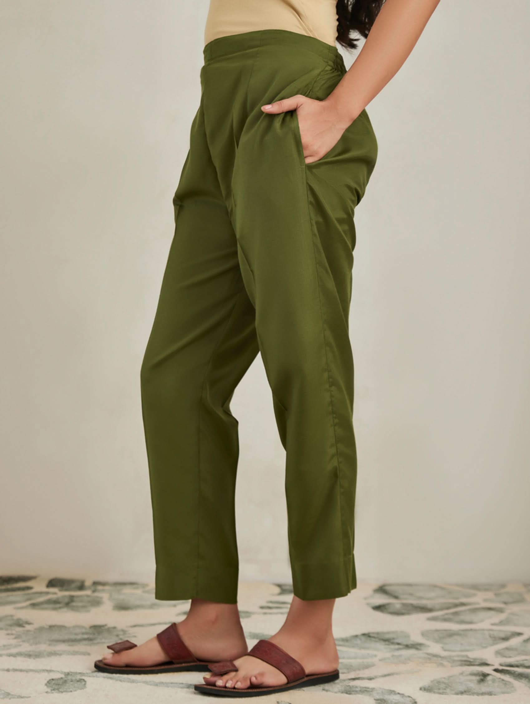 Person wearing green pants standing on a patterned floor.