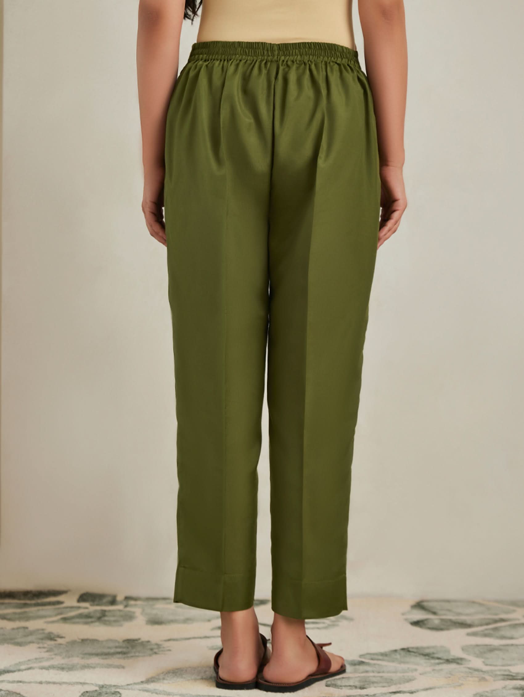 Person wearing olive green pants on a neutral background
