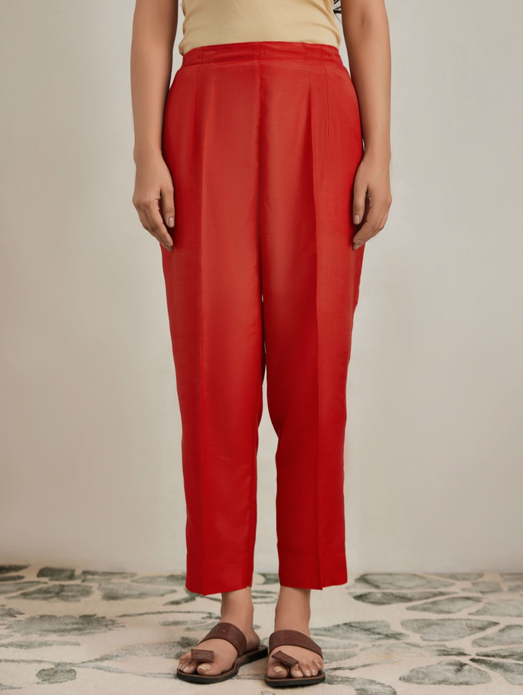 Person wearing red pants standing on a patterned floor.