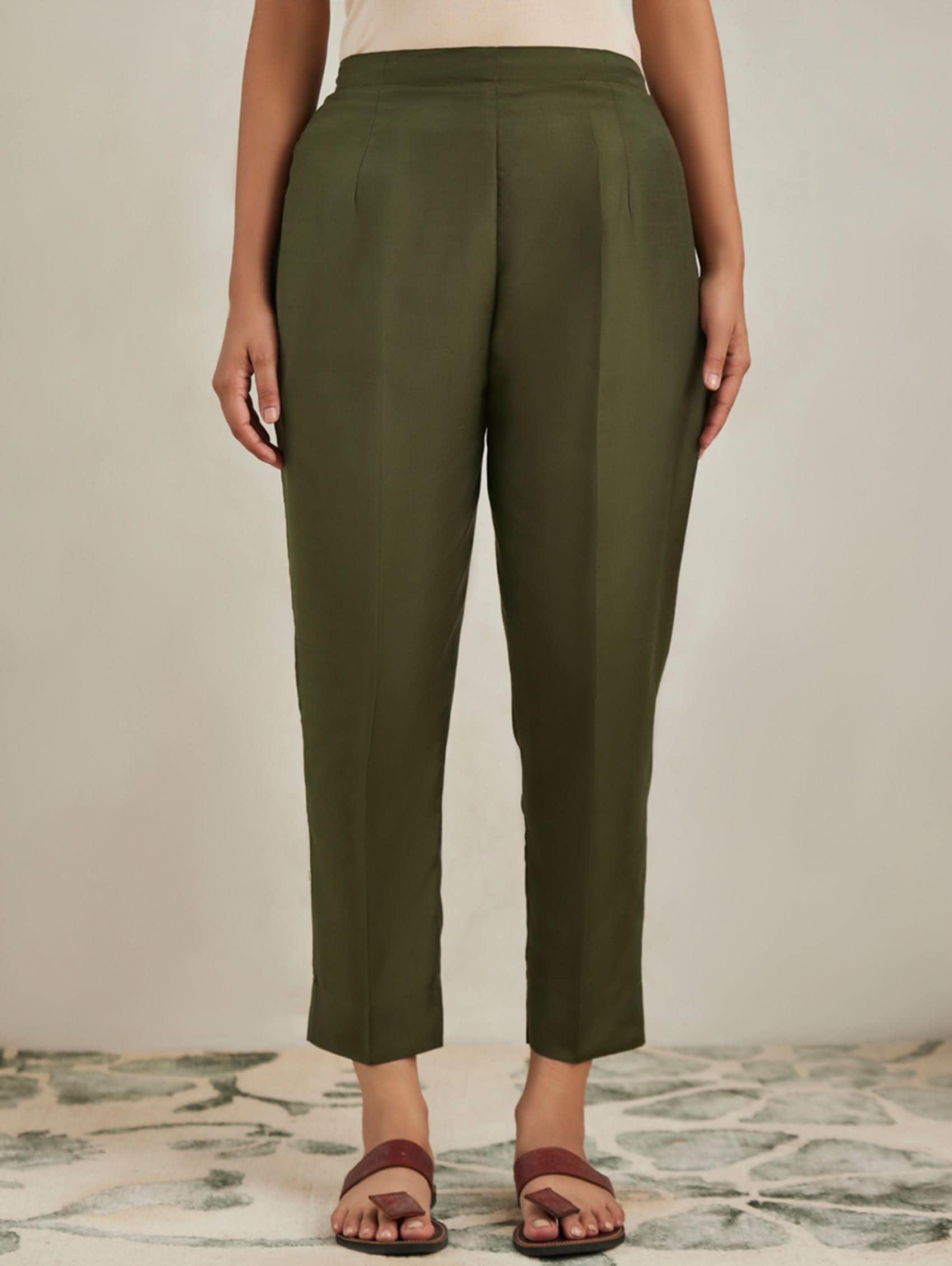Person wearing olive green pants on a neutral background