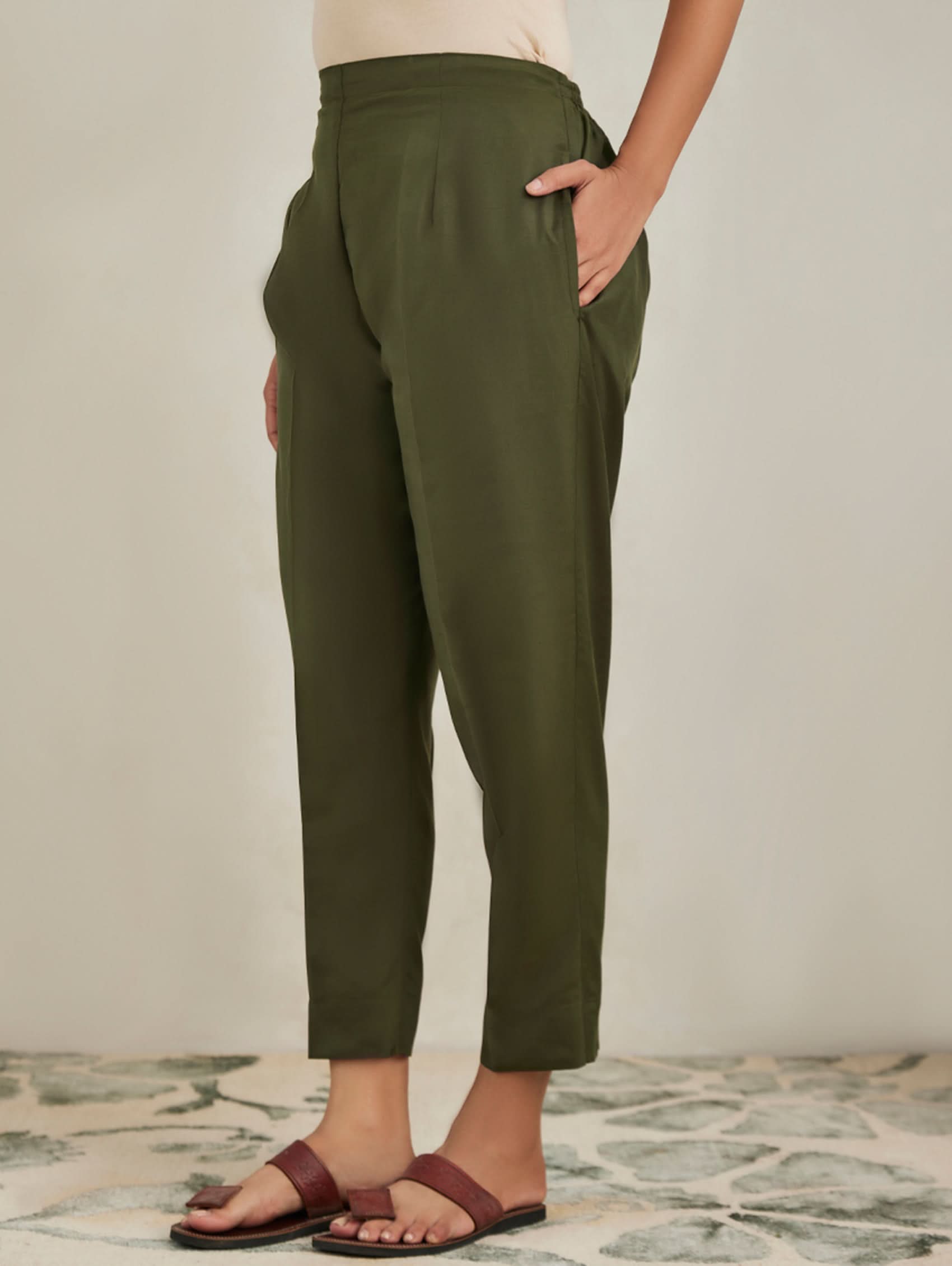 Person wearing olive green pants with a neutral background