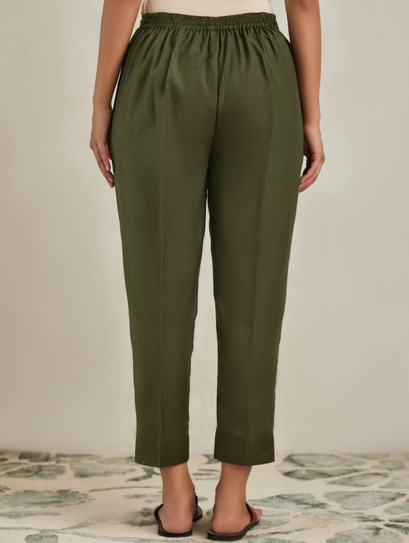 Person wearing olive green pants on a neutral background