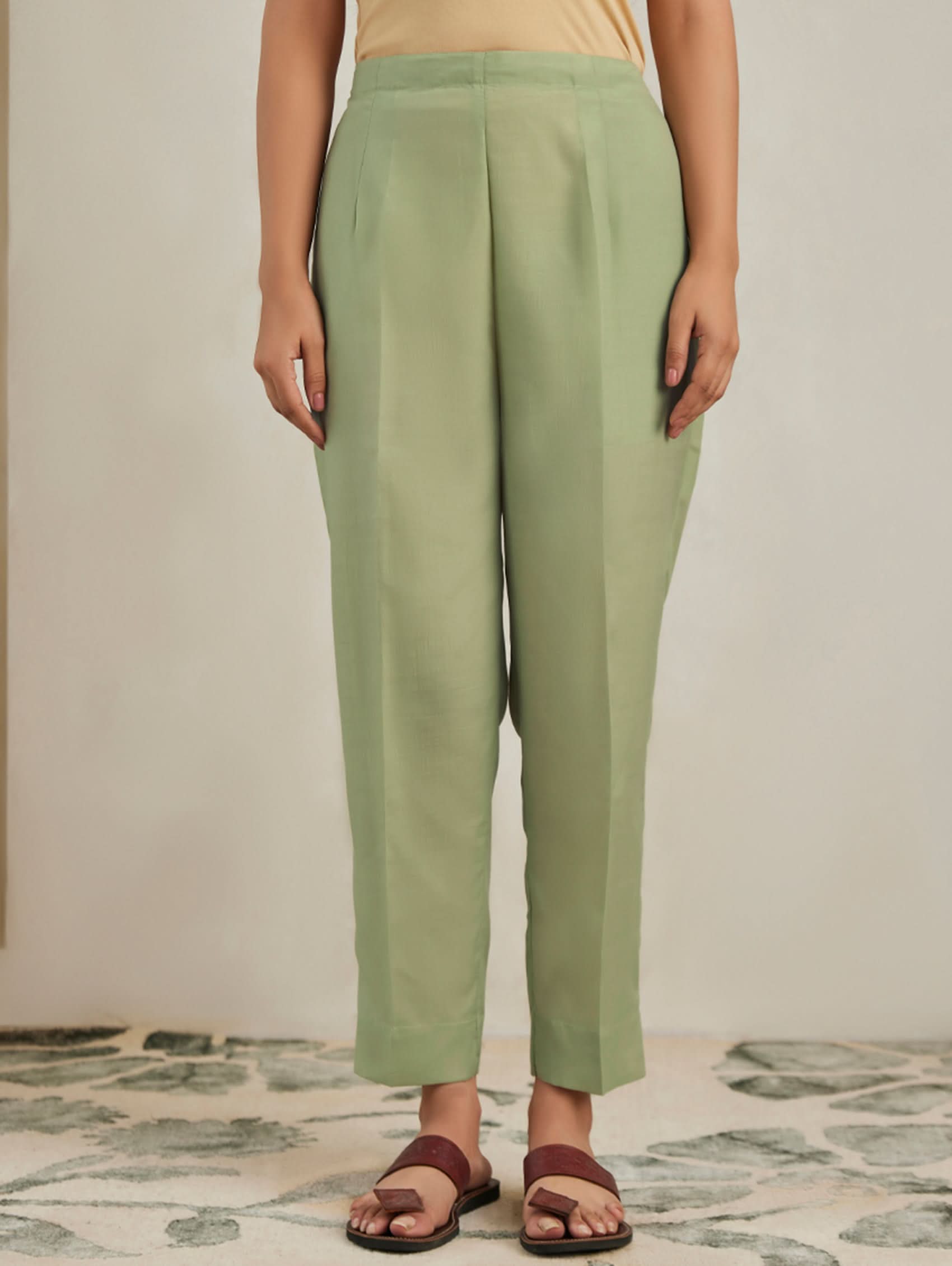 Person wearing green pants standing on a patterned floor.