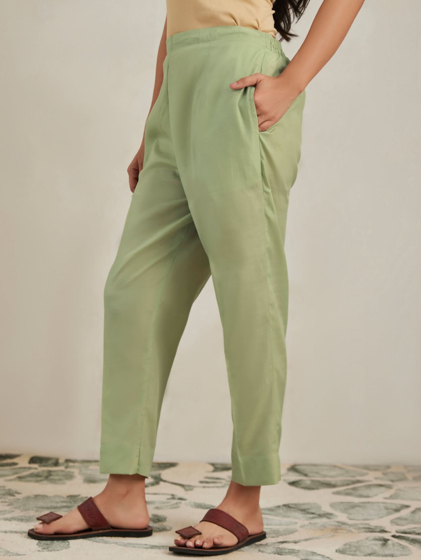 Person wearing light green pants with a neutral background