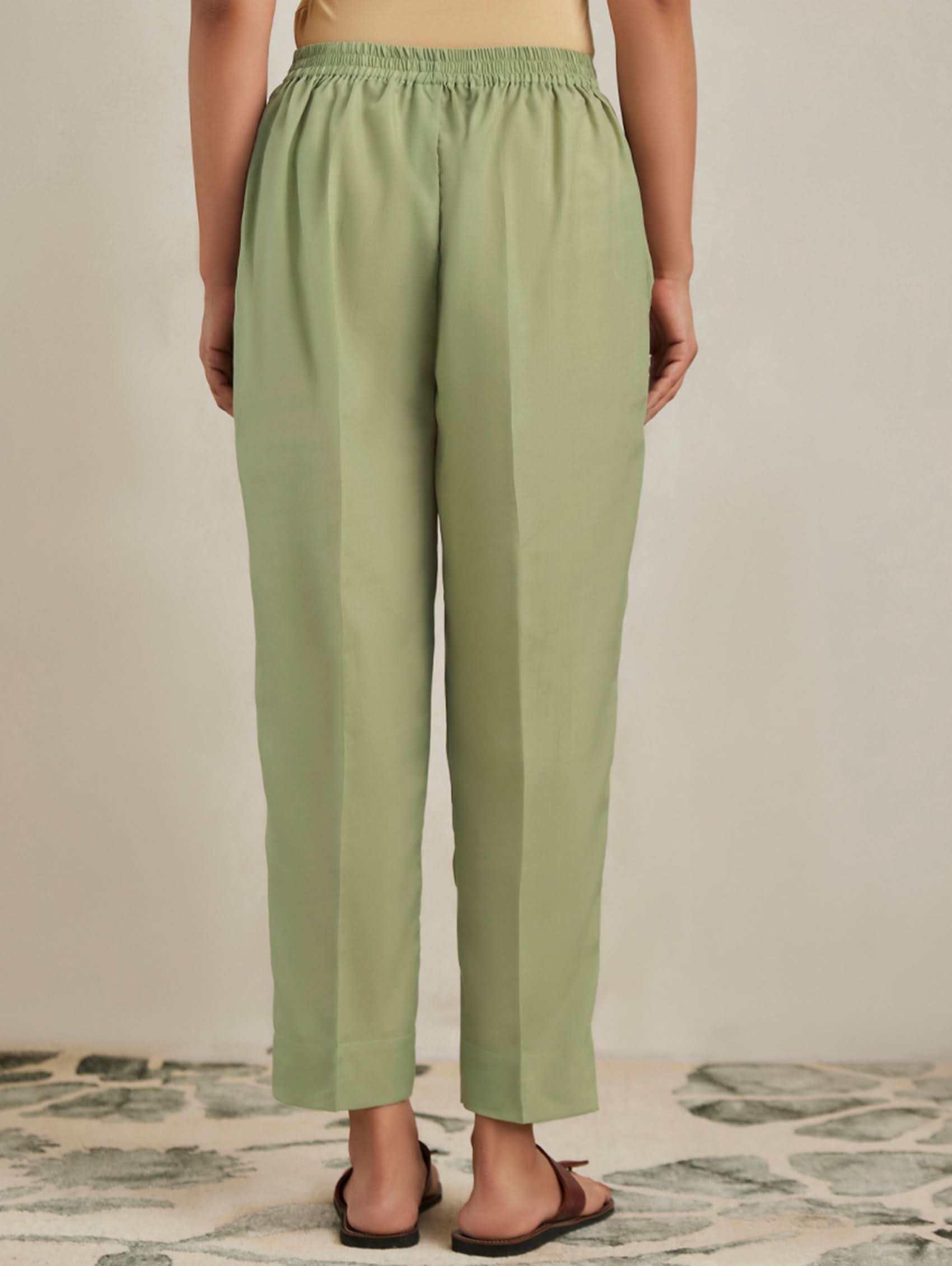 Person wearing green pants on a neutral background