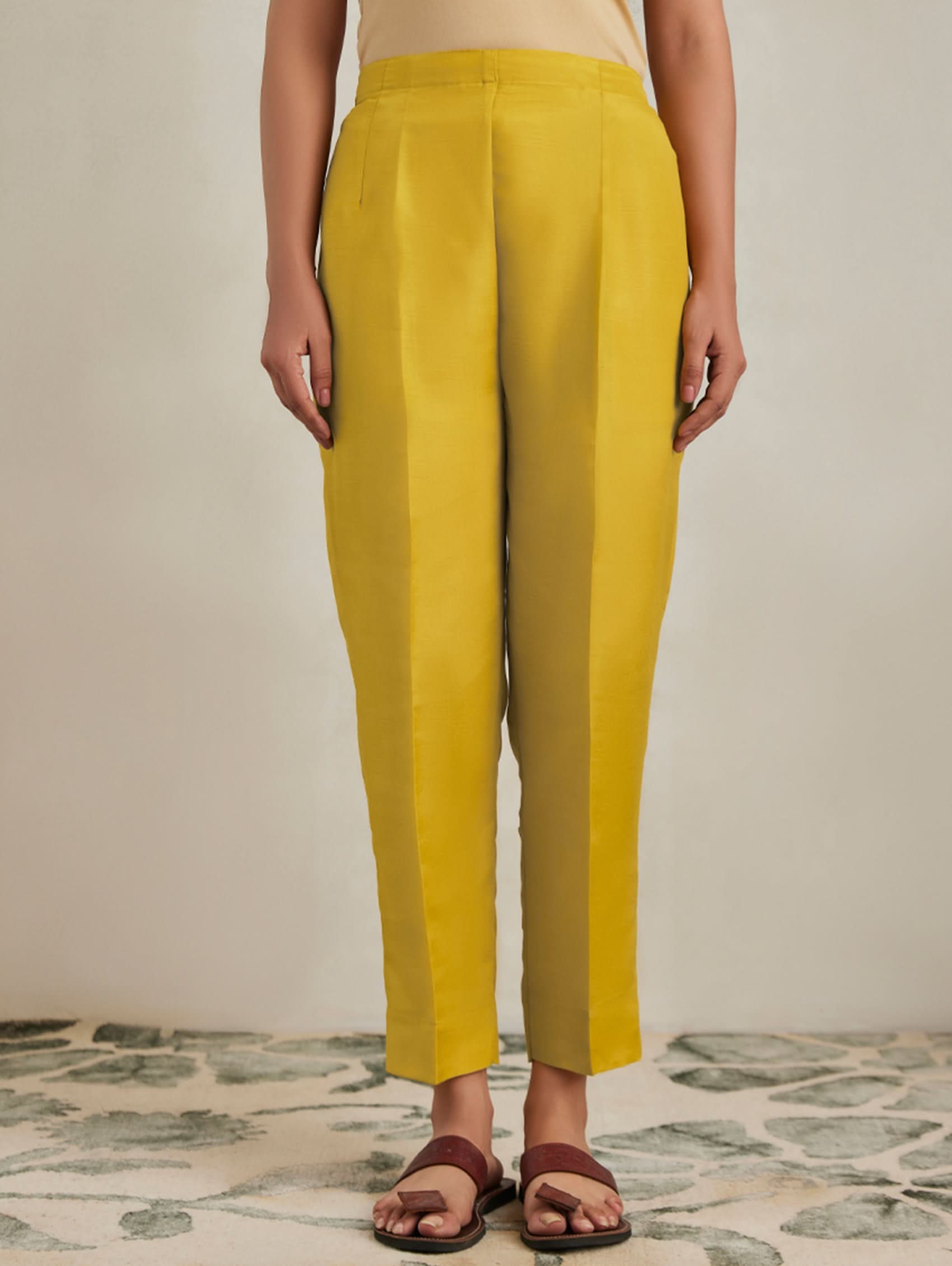 Person wearing mustard yellow pants on a neutral background