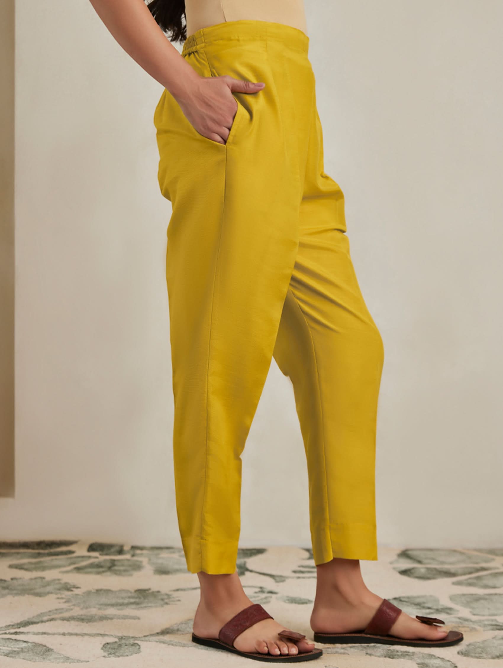 Person wearing mustard yellow pants on a neutral background