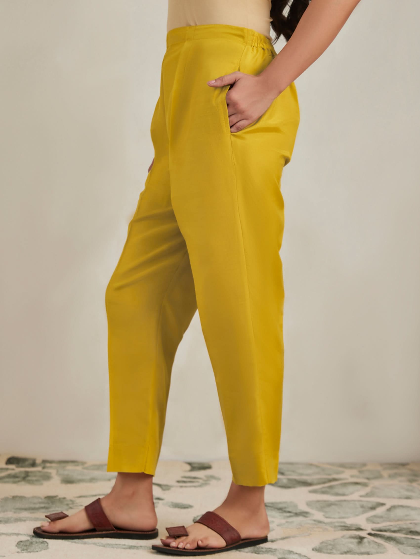 Person wearing mustard yellow pants with a neutral background