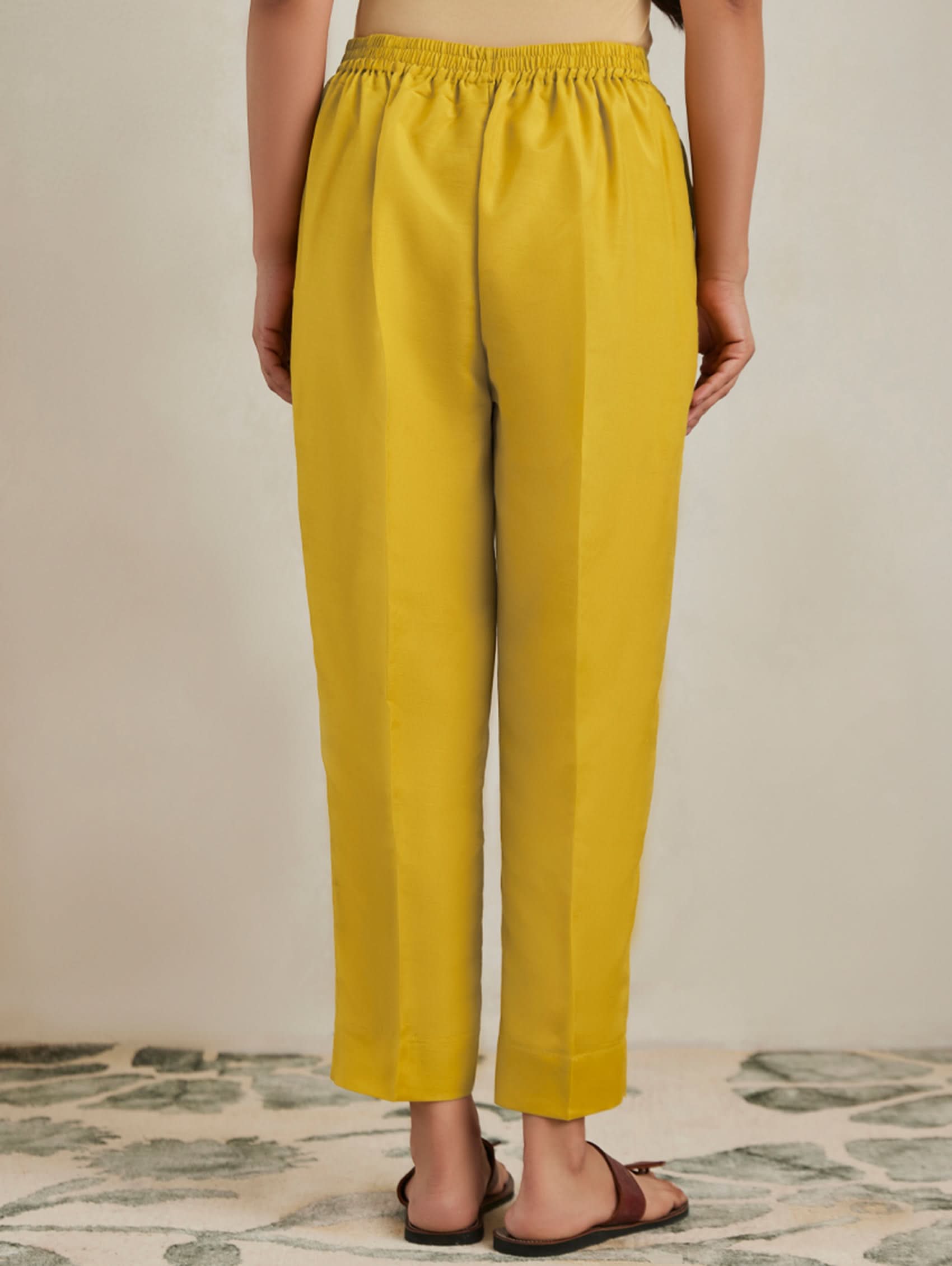 Person wearing mustard yellow pants on a neutral background