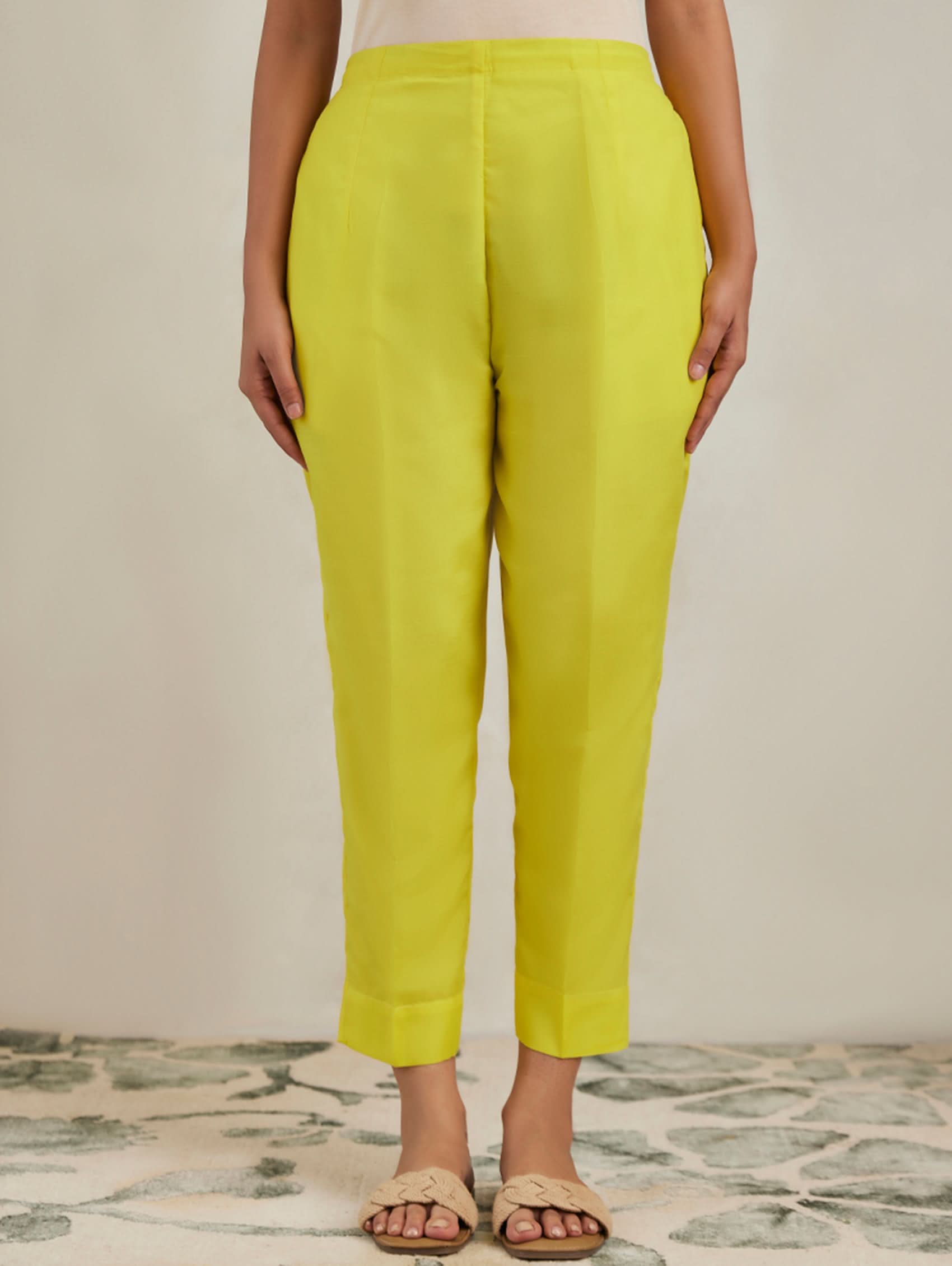 Person wearing bright yellow pants on a neutral background