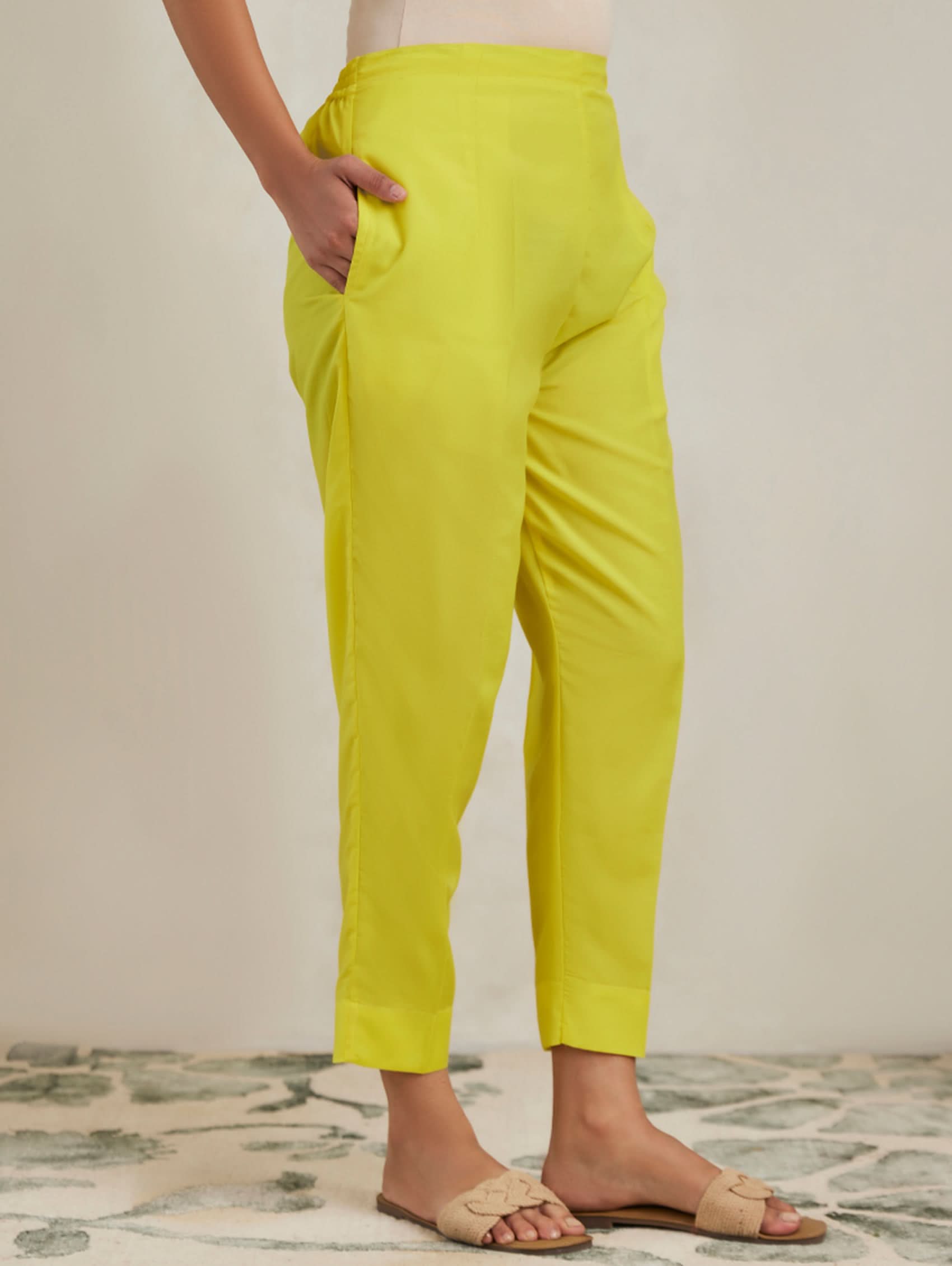 Person wearing bright yellow pants on a neutral background