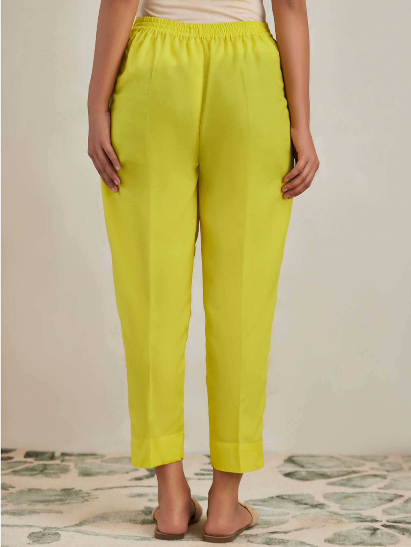 Person wearing bright yellow pants on a neutral background