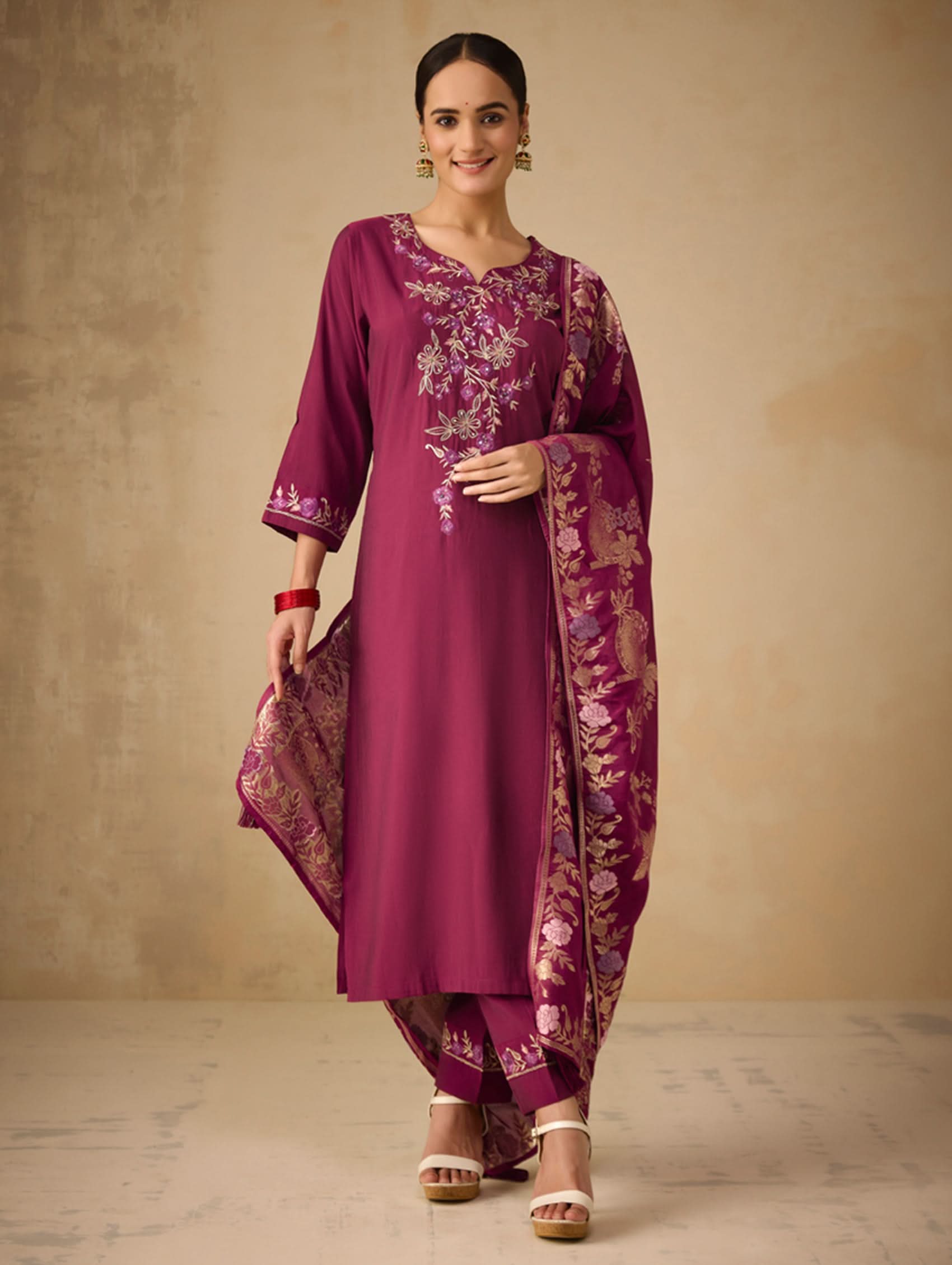 Woman wearing a traditional purple outfit with floral patterns on a beige background