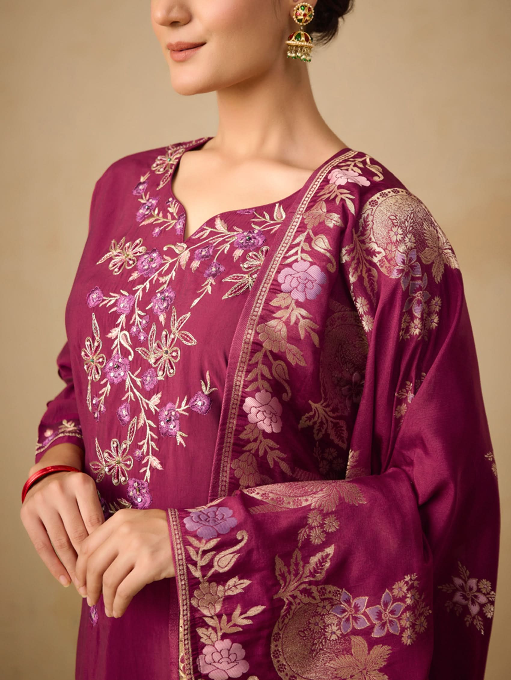Purple embroidered traditional outfit with floral patterns on a beige background