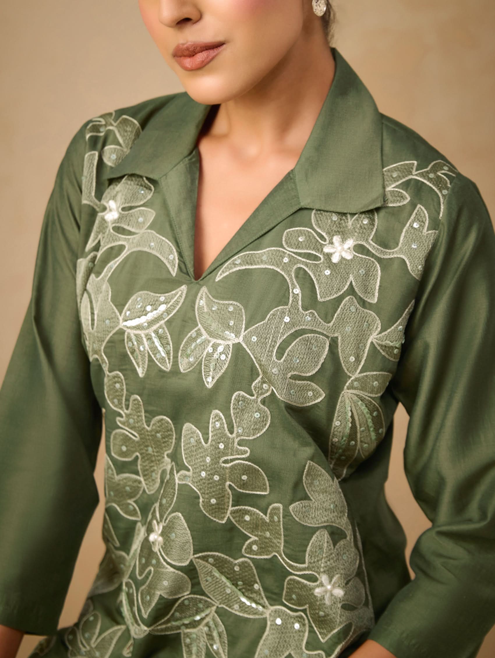 Green shirt with floral embroidery on a beige background