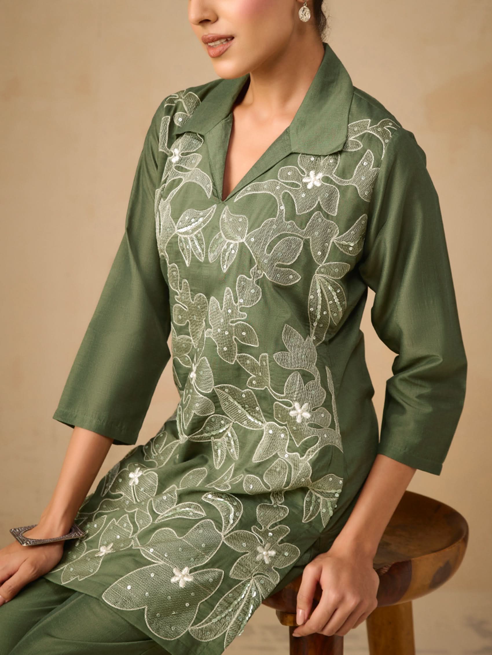 Green dress with floral embroidery on a beige background