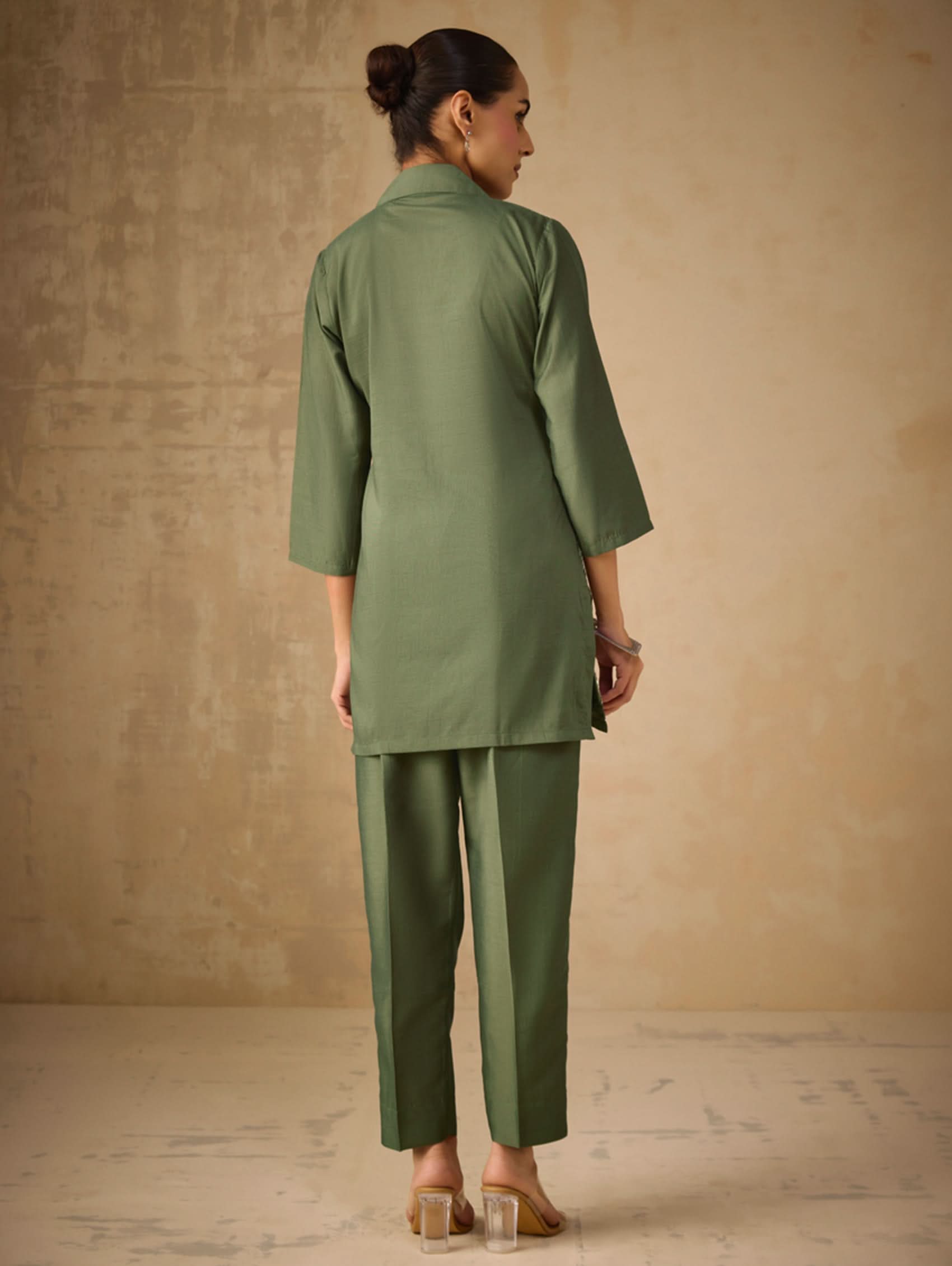 Woman wearing a green outfit against a beige background
