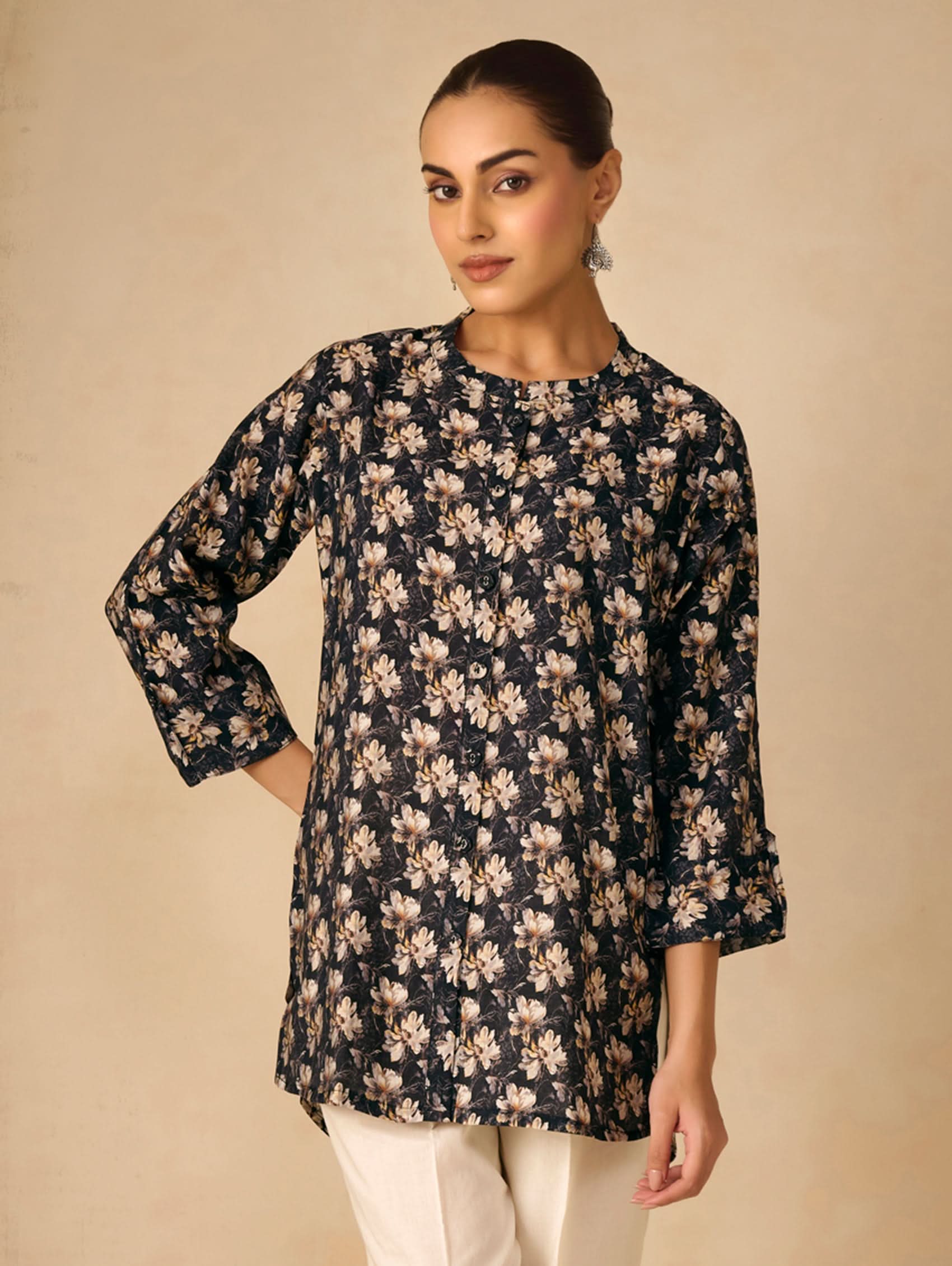Woman wearing a black floral long-sleeve top against a beige background