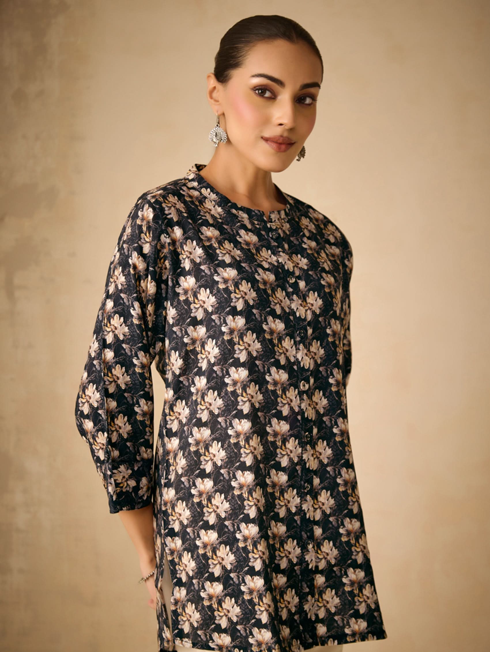 Woman wearing a black floral dress against a beige background