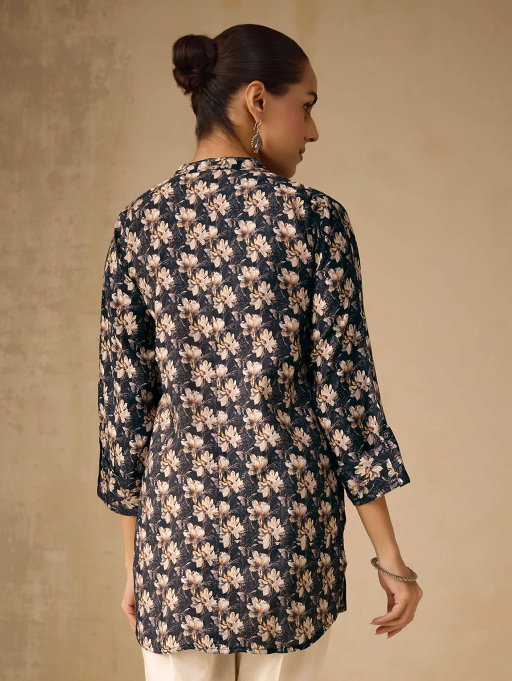 Woman wearing a floral patterned shirt against a beige background