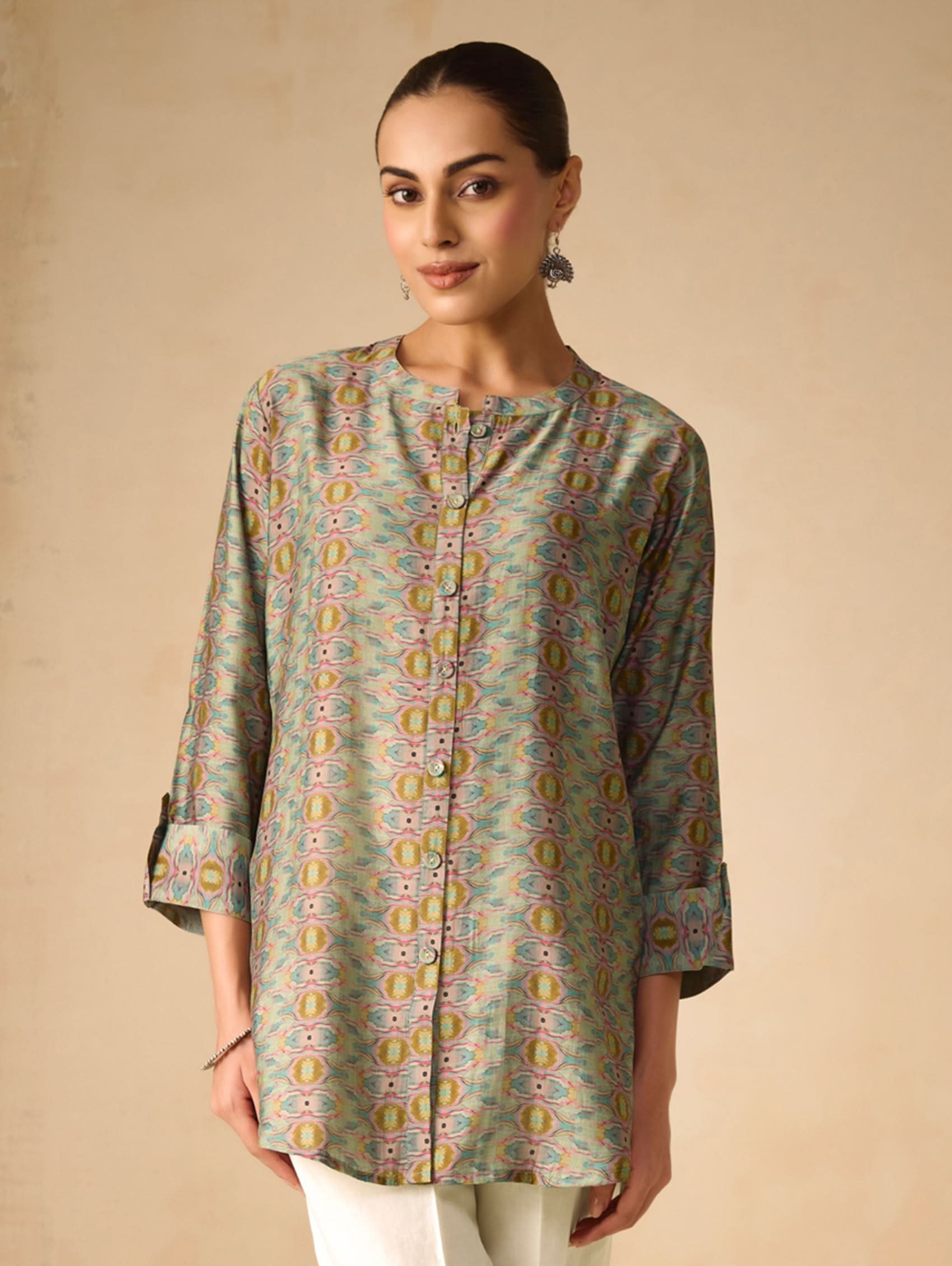 Woman wearing a patterned green shirt against a beige background